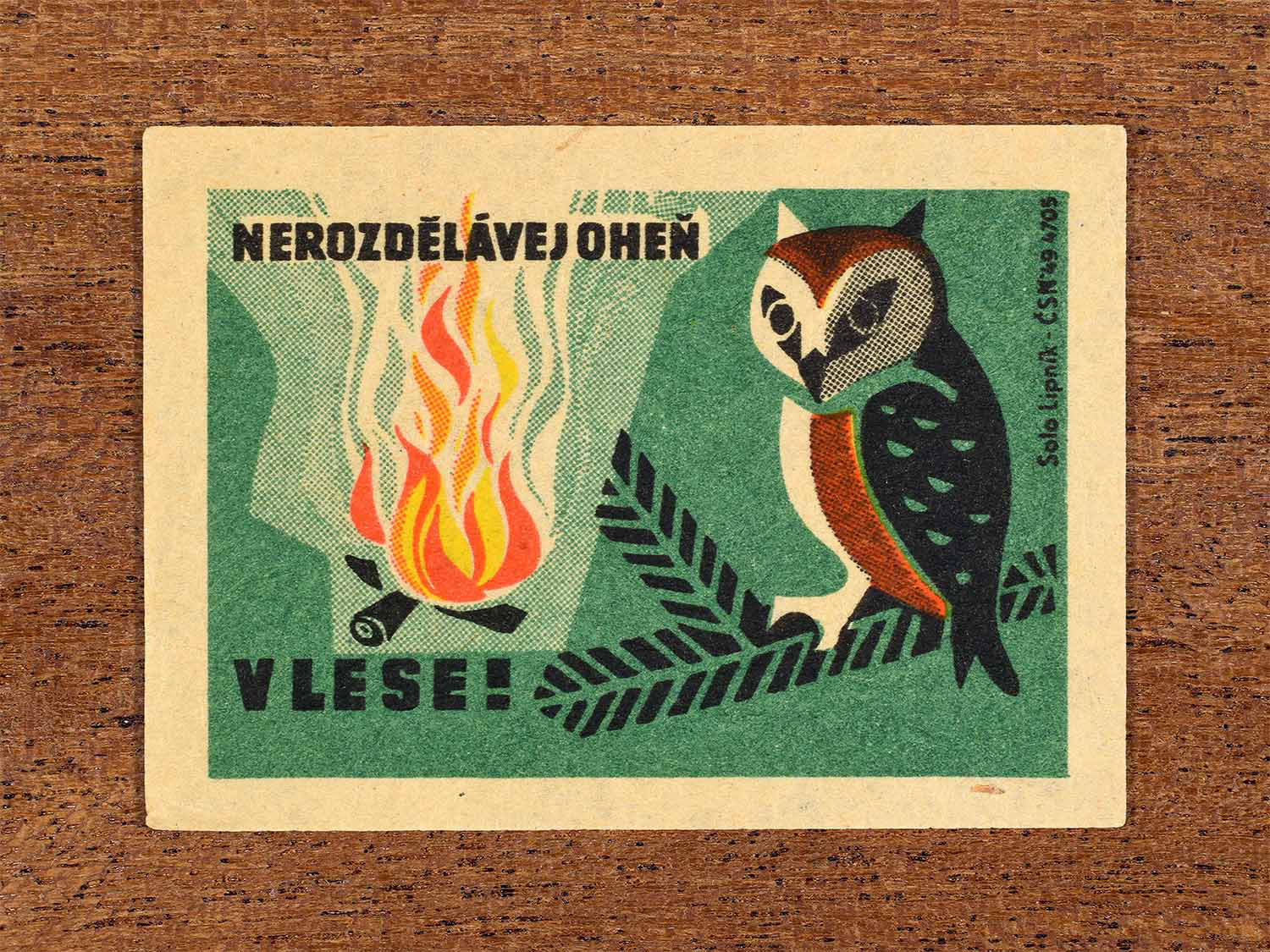Vintage 1964 Czech matchbox label showing a burning forest scene with an owl, in yellow, orange and green colours. Produced by the Solo Lipník match factory to warn against lighting fires in forests.