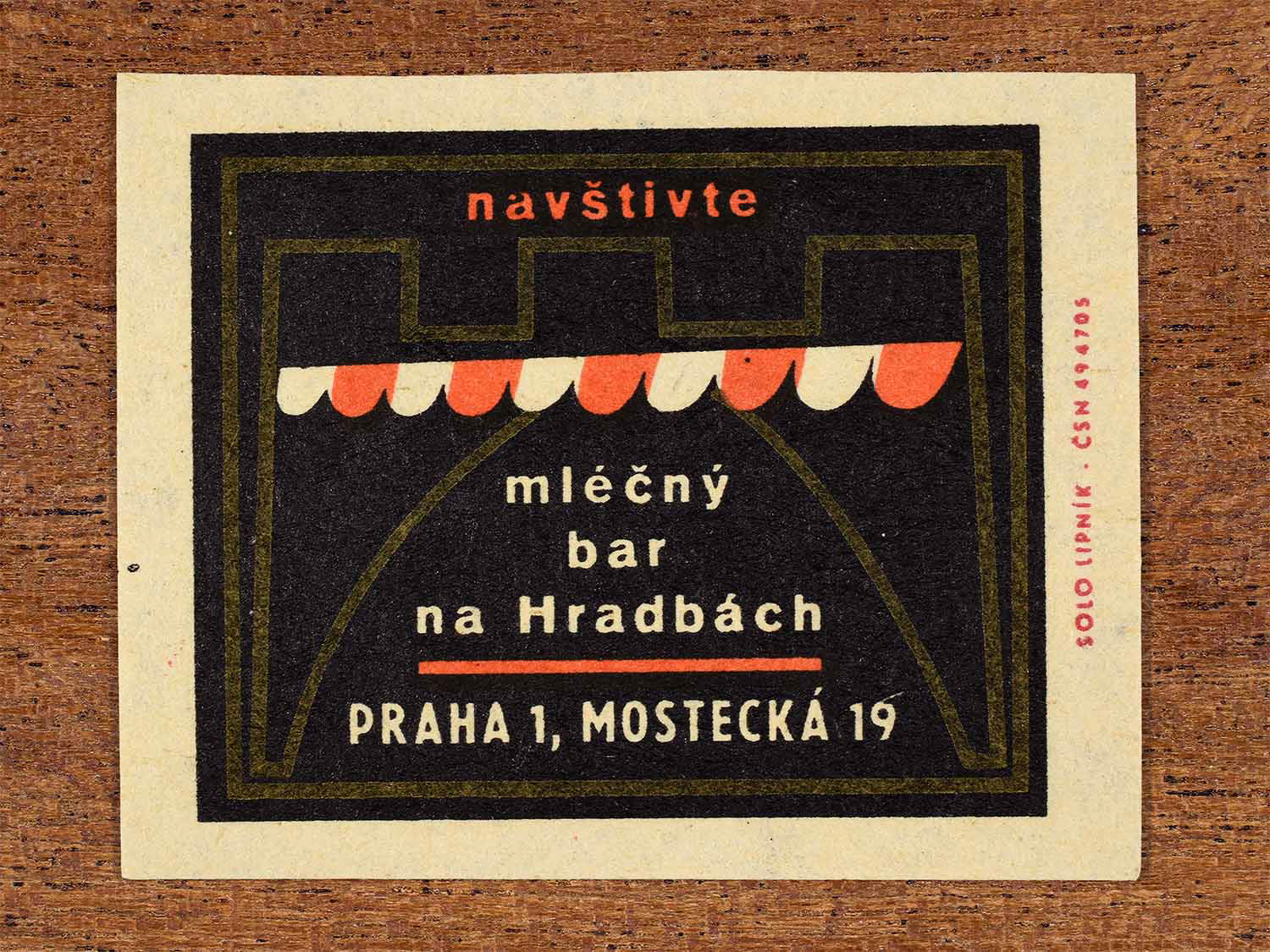 Vintage c. 1967 Czech matchbox labels showing a stylised shop entrance on a black background. Produced by the Solo Lipník match factory to promote a dairy bar in Prague.
