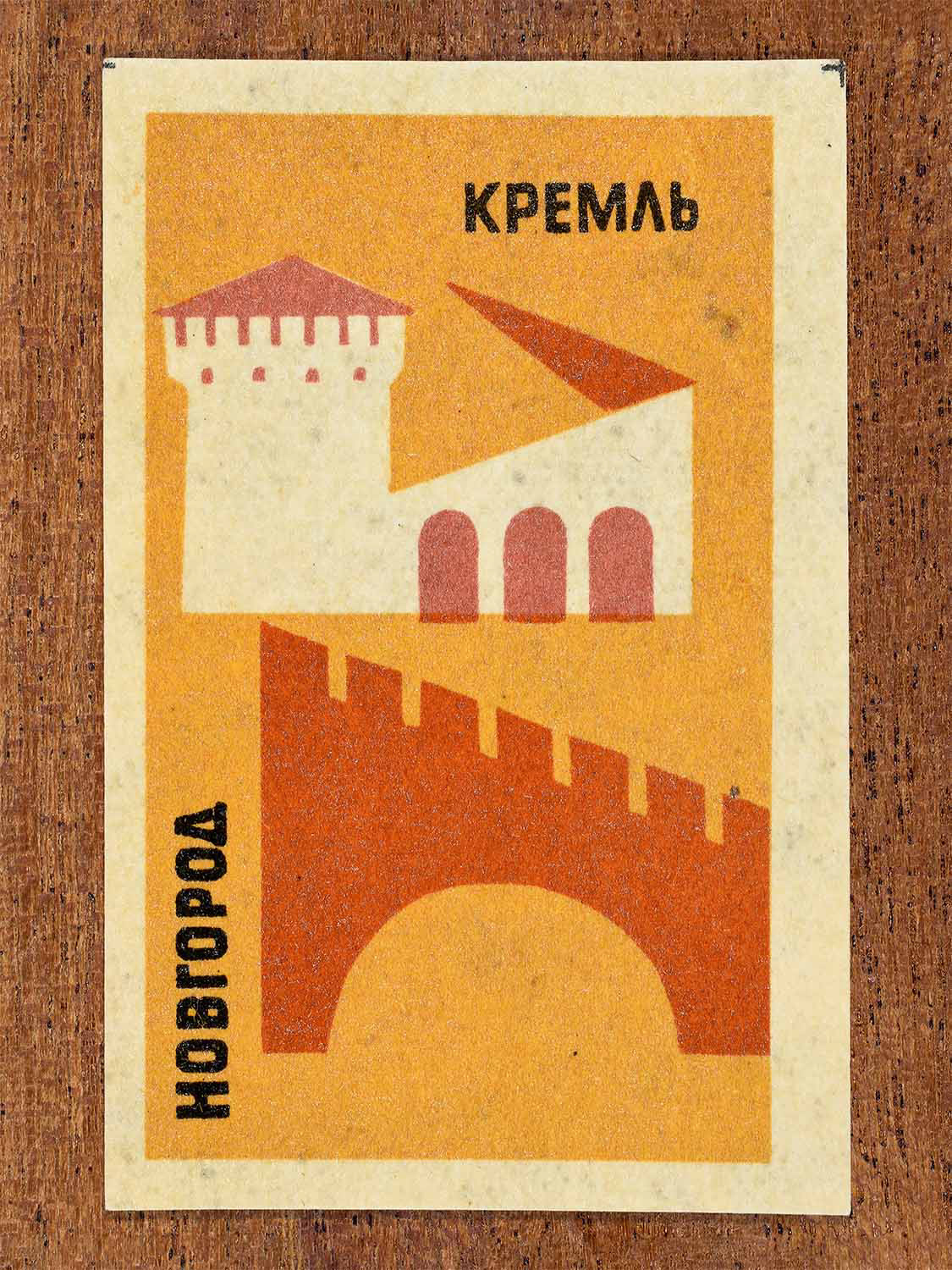 Vintage 1966 Soviet matchbox label showing a geometric illustration of the Novgorod Kremlin with fortress walls and tower. Produced by a Soviet match factory to commemorate historic Russian architecture.