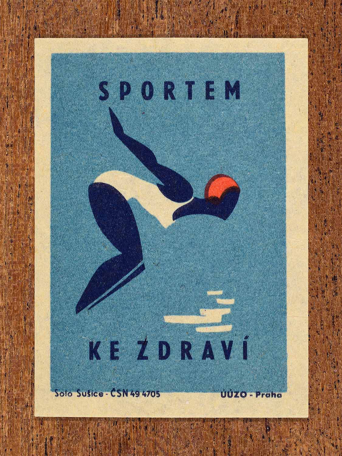 Vintage c. 1964 Czech matchbox label showing a stylised diving figure in motion in blue and red colours. Produced by the Solo Sušice match factory to promote sport as a path to better health.