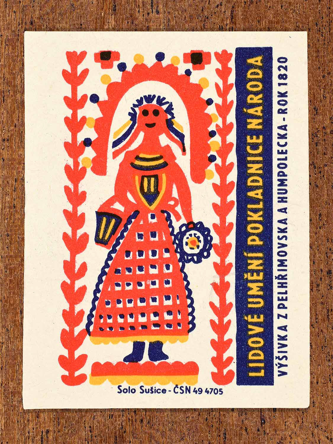 Vintage 1964 Czech matchbox label showing a single stylised female figure framed by vertical floral borders. Produced by the Solo Sušice match factory to present Pelhřimov regional embroidery.