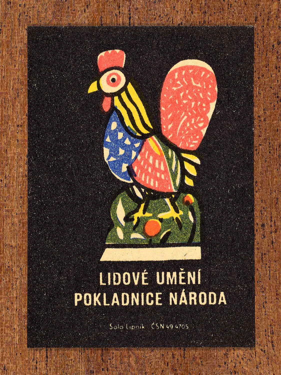 Vintage c. 1962 Czech matchbox label showing a brightly coloured stylised folk rooster with ornamental patterning. Produced by the Solo Lipník match factory to highlight traditional rural folk symbolism.