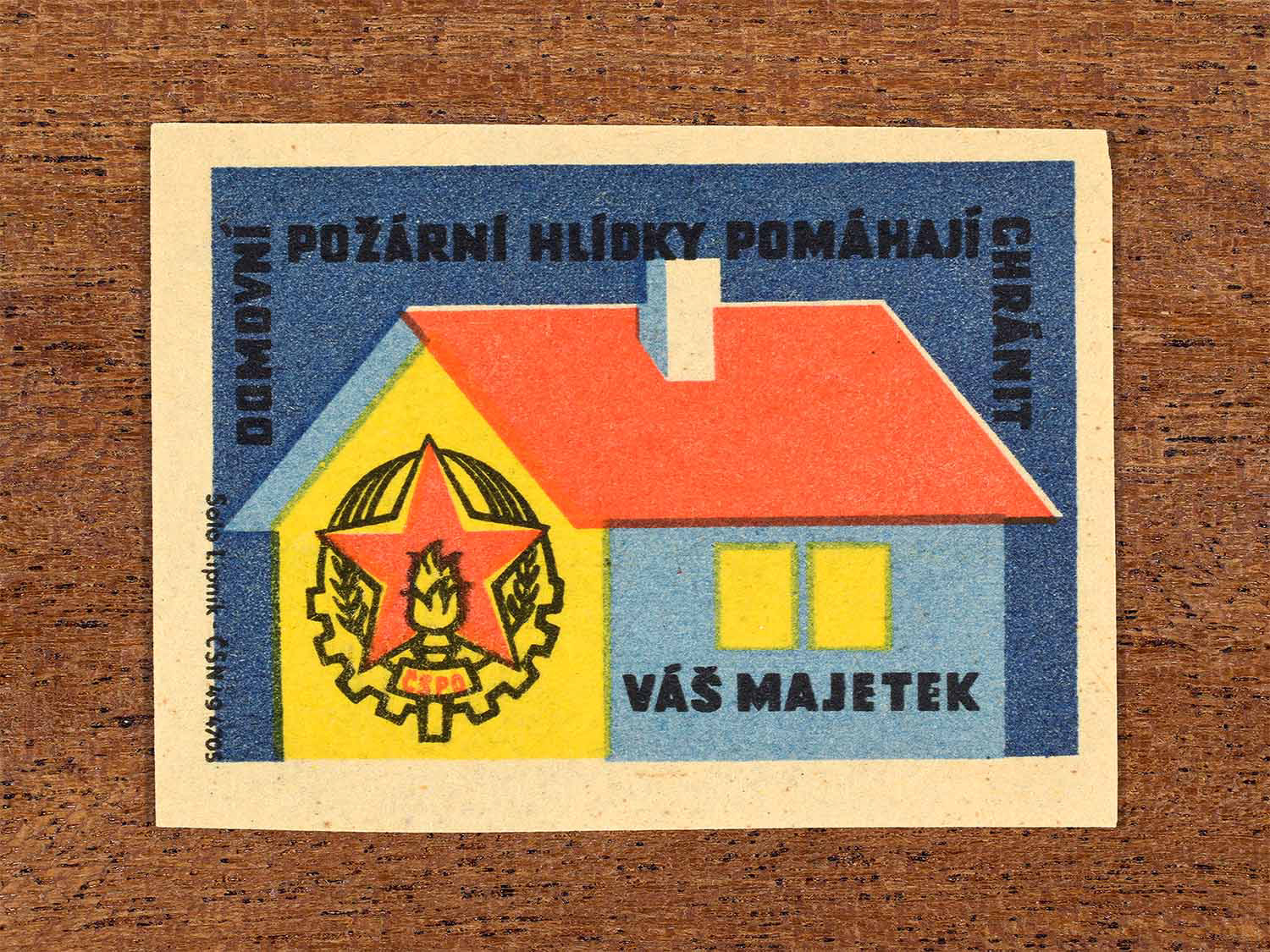 Vintage 1964 Czech matchbox label showing a fire brigade emblem and a house in red, yellow and blue colours. Produced by the Solo Lipník match factory to promote fire patrols protecting private property.