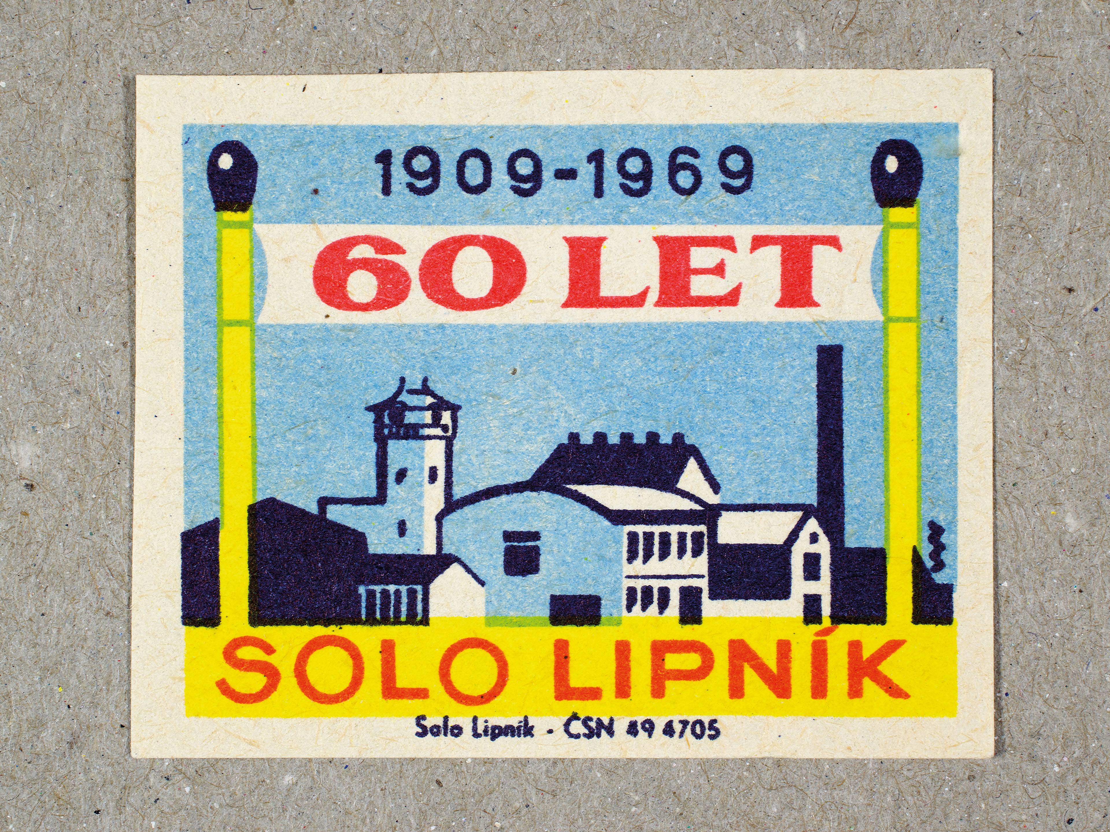 Vintage 1969 Czech matchbox label by Solo Lipník featuring a banner being held up by matchsticks and standing over a building. Part of the 'SOLO Lipník Anniversary' series advertising the Czechoslovakian match factory.