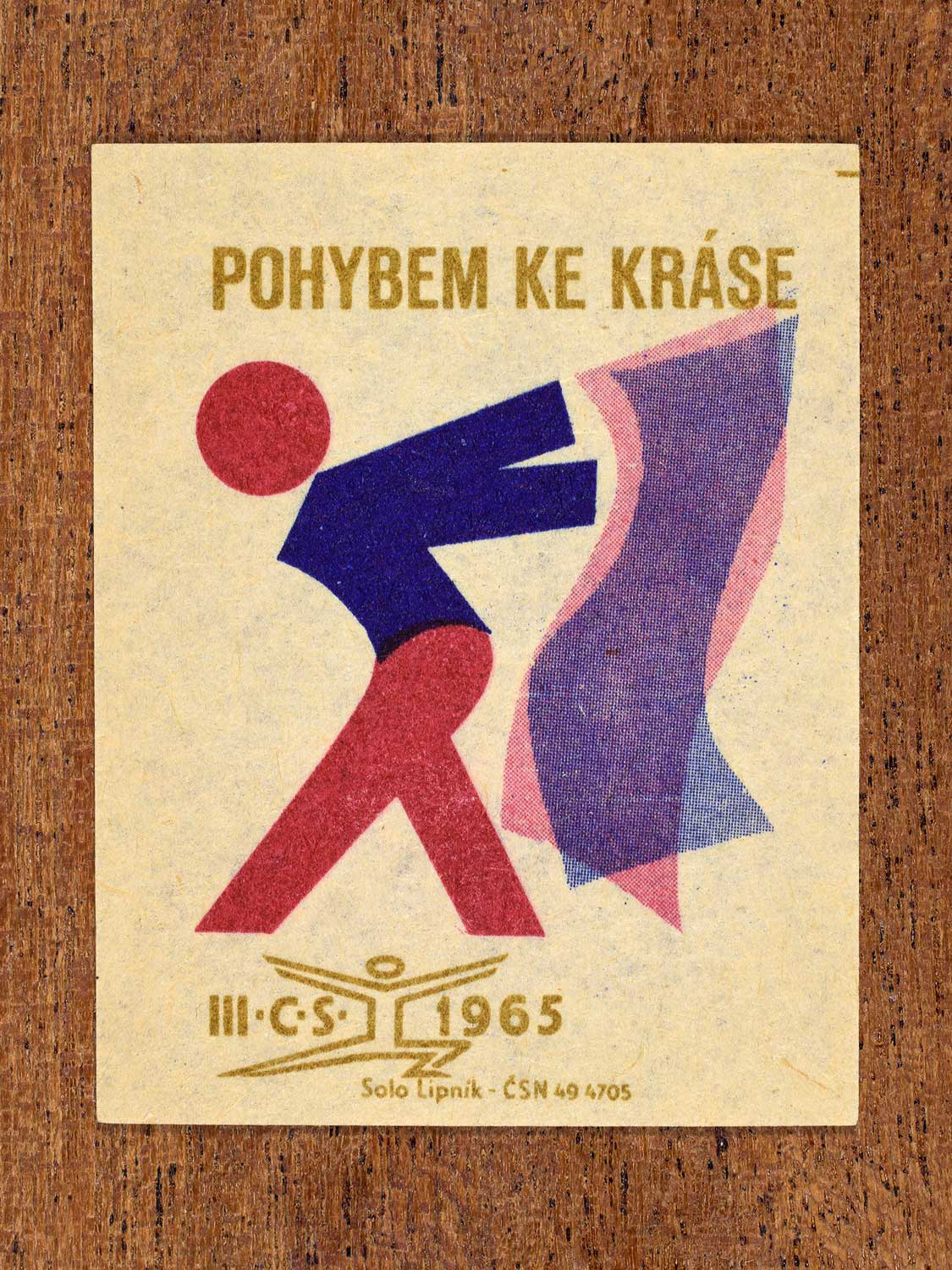 Vintage 1965 Czechoslovak matchbox label showing a stylised figure in graceful motion. In blue, red and gold colours. Produced by the Solo Lipník match factory to promote physical movement as a path to beauty.