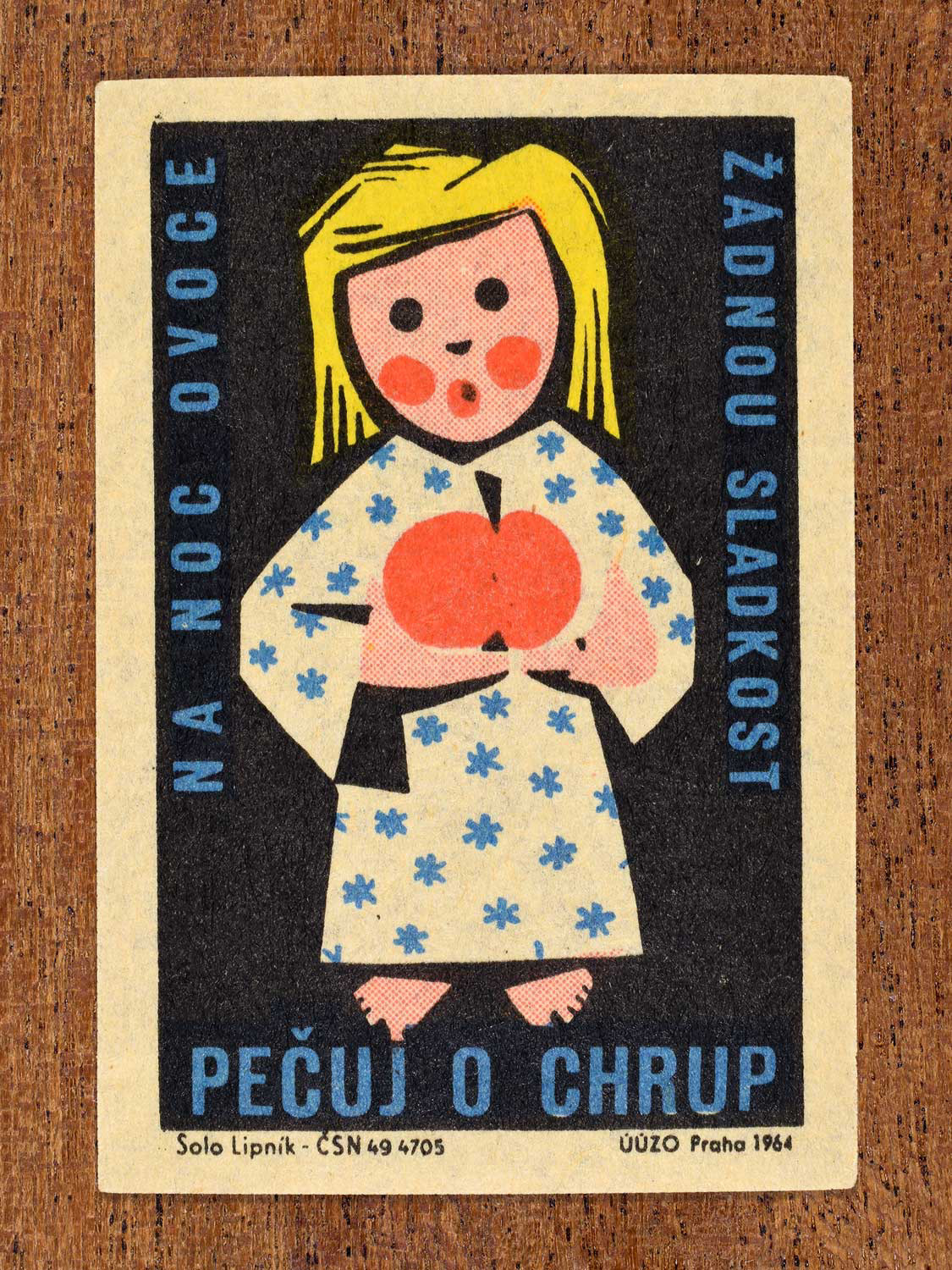 Vintage 1964 Czech matchbox label showing an illustrated child holding fruit, on a black background. Produced by the Solo Lipník match factory to promote nutrition advice and hygiene habits in protecting healthy teeth.