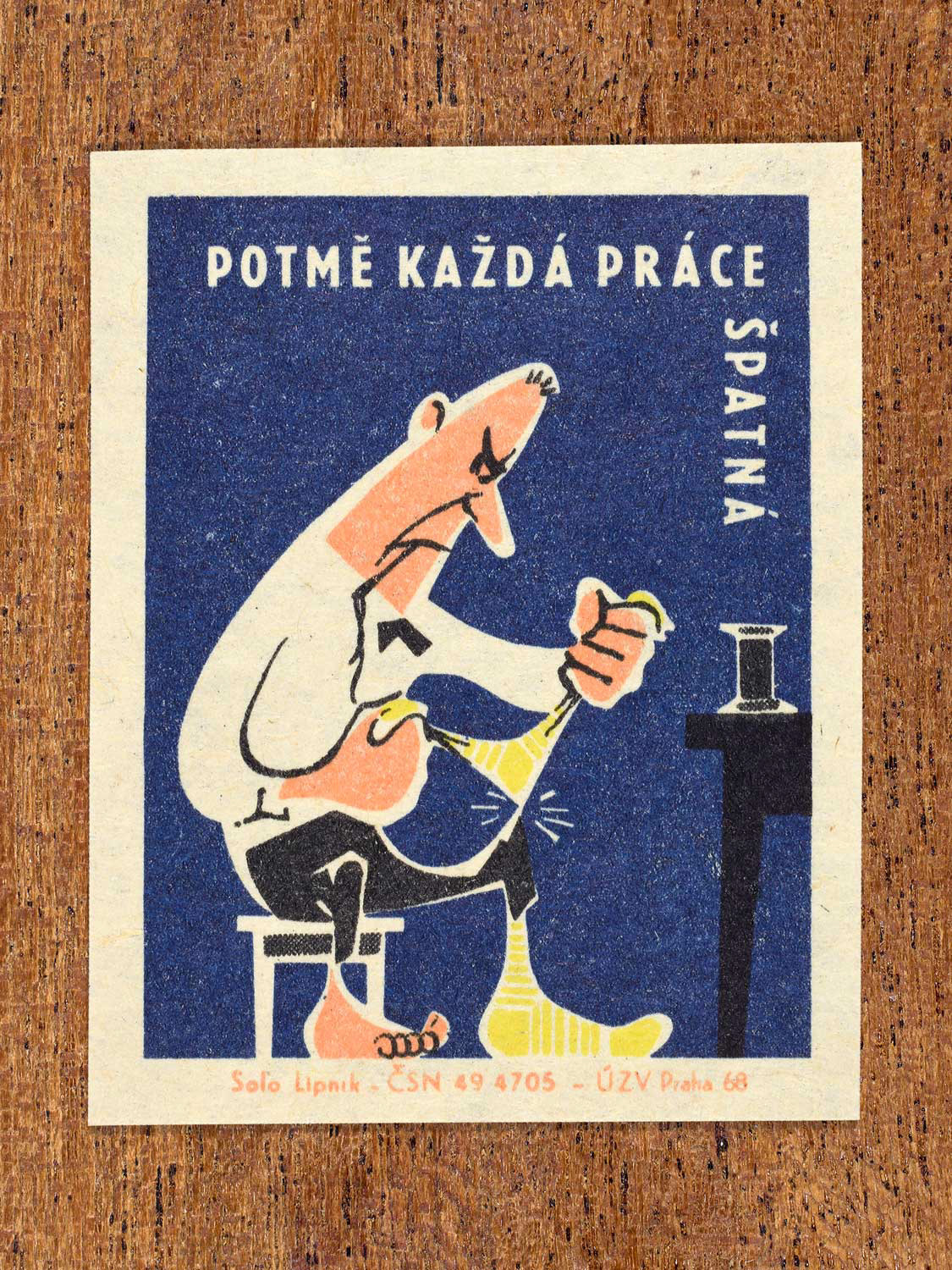 Vintage 1968 Czech matchbox label featuring a cartoon person struggling with a yellow sock, on blue background. Produced by Solo Lipník match factory to promote proper lighting and maintenance for eye health and safe work practices.