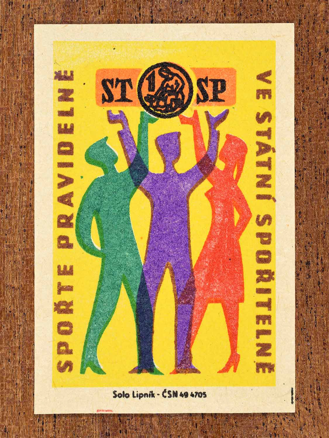 Vintage 1960 Czech matchbox label showing three stylised figures raising their arms in bright colours. Produced by the Solo Lipník match factory to promote regular saving in the State Savings Bank.