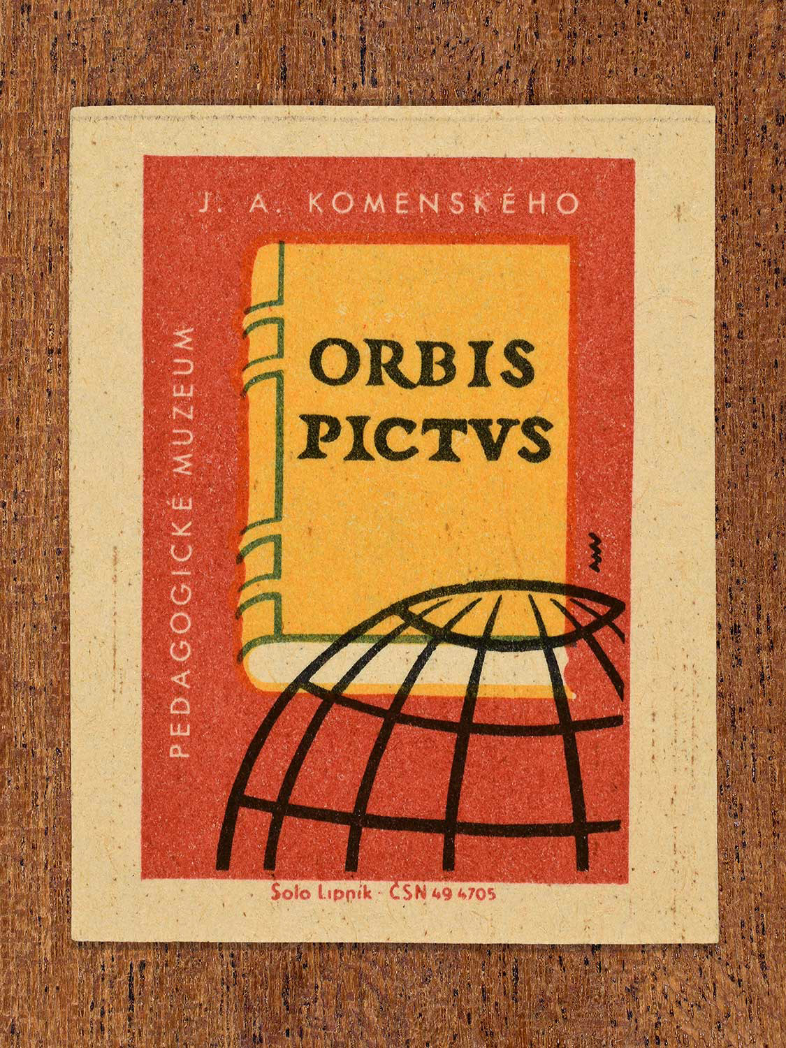 Vintage 1964 Czechoslovakia matchbox label showing a stylised book cover titled 'Orbis Pictus' next to a wireframe globe in black, yellow, teal and red colours. Produced by the Solo Lipník match factory to promote the Pedagogické Muzeum J. A. Komenského (National Pedagogical Museum & Library of J. A. Comenius) in Czechoslovakia.