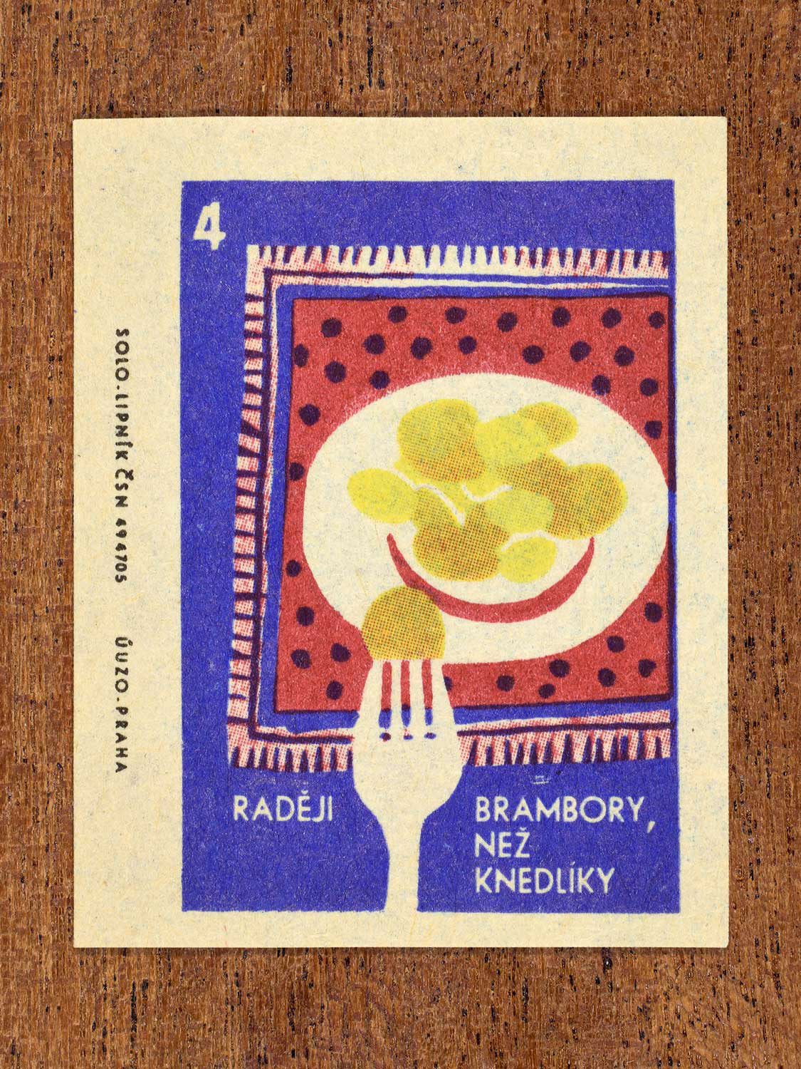 Vintage c. 1965 Czech matchbox label showing a plate full of potatoes and a folk arranged on a red tablecloth. Produced by Solo Lipník match factory to promote the health benefits proper nutrition, daily meal routines, and everyday household habits.