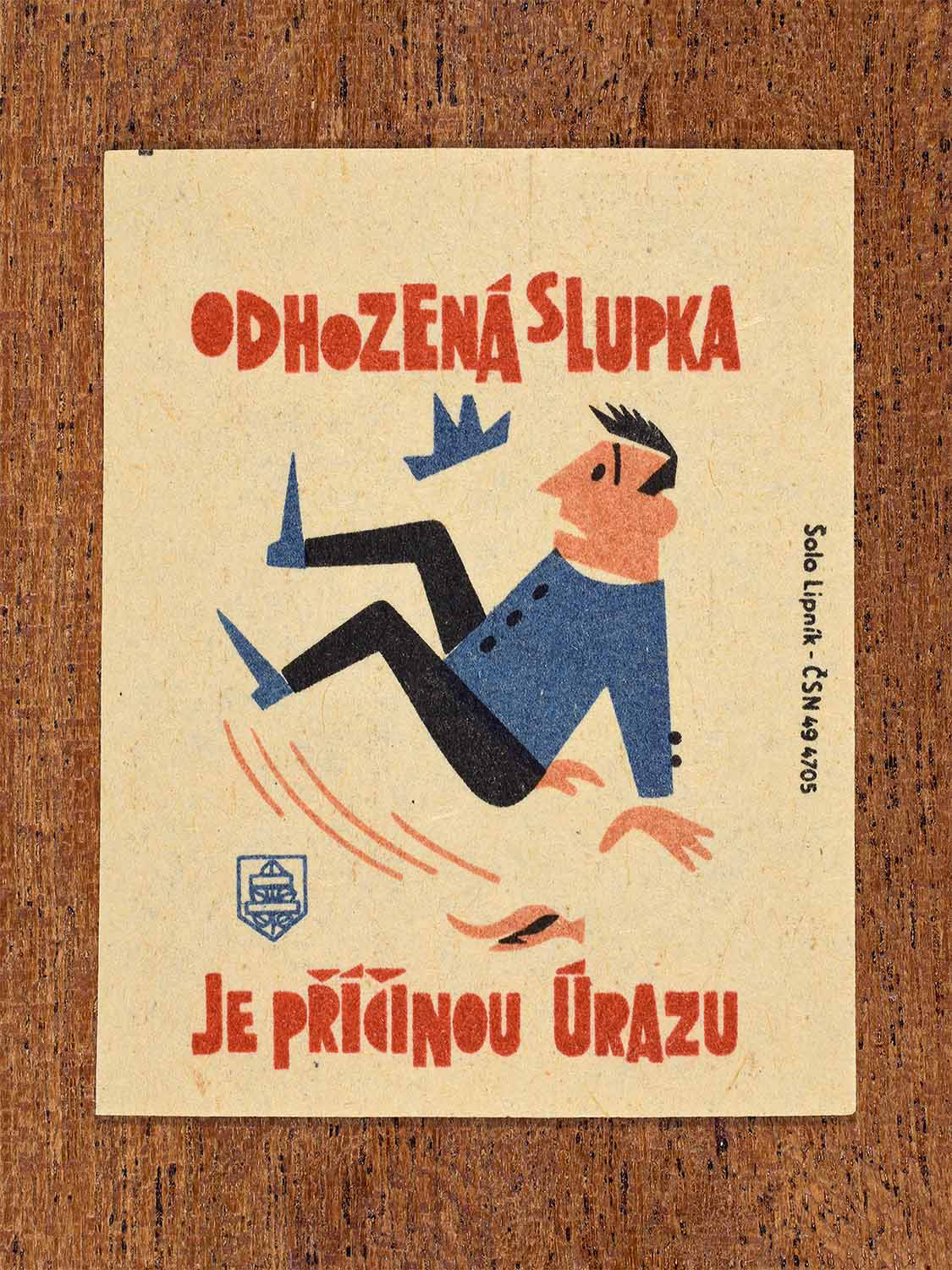 Vintage 1964 Czech matchbox label showing a person slipping on a discarded peel, in blue, red and black colours. Produced by the Solo Lipník match factory to warn against careless littering that can cause accidents.