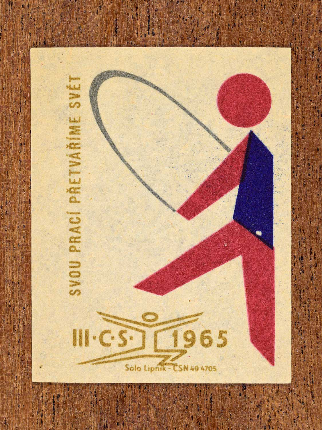 Vintage 1965 Czechoslovak matchbox label showing an abstract athlete figure, in blue, red and gold colours. Produced by the Solo Lipník match factory to promote physical fitness and sporting achievement.