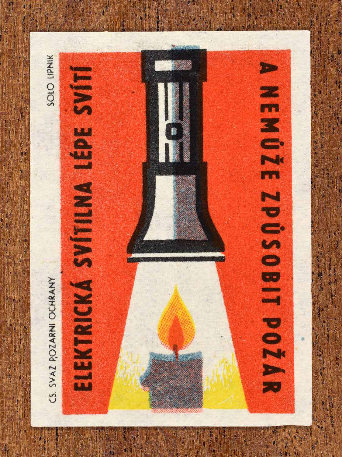 Vintage 1963 Czech matchbox label showing a flashlight shining over a candle flame in red, yellow and black colours. Produced by the Solo Lipník match factory to promote safer electric lighting over open flames.