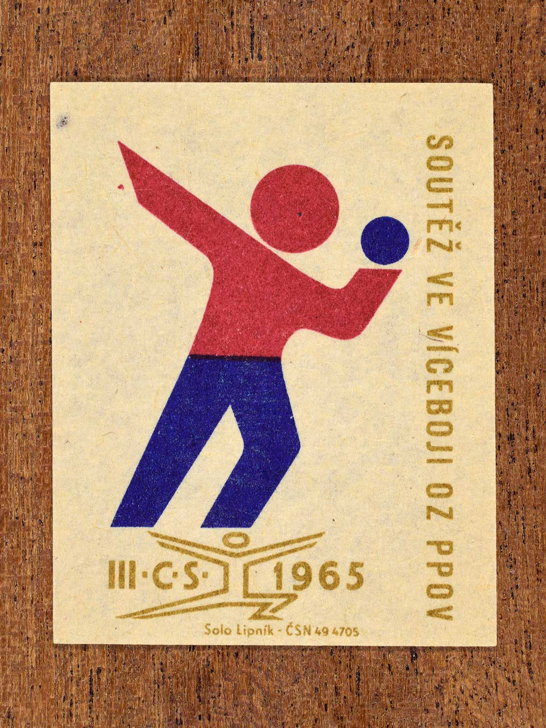 Vintage 1965 Czechoslovak matchbox label showing an abstract athlete figure, in blue, red and gold colours. Produced by the Solo Lipník match factory to promote physical fitness and sporting achievement.