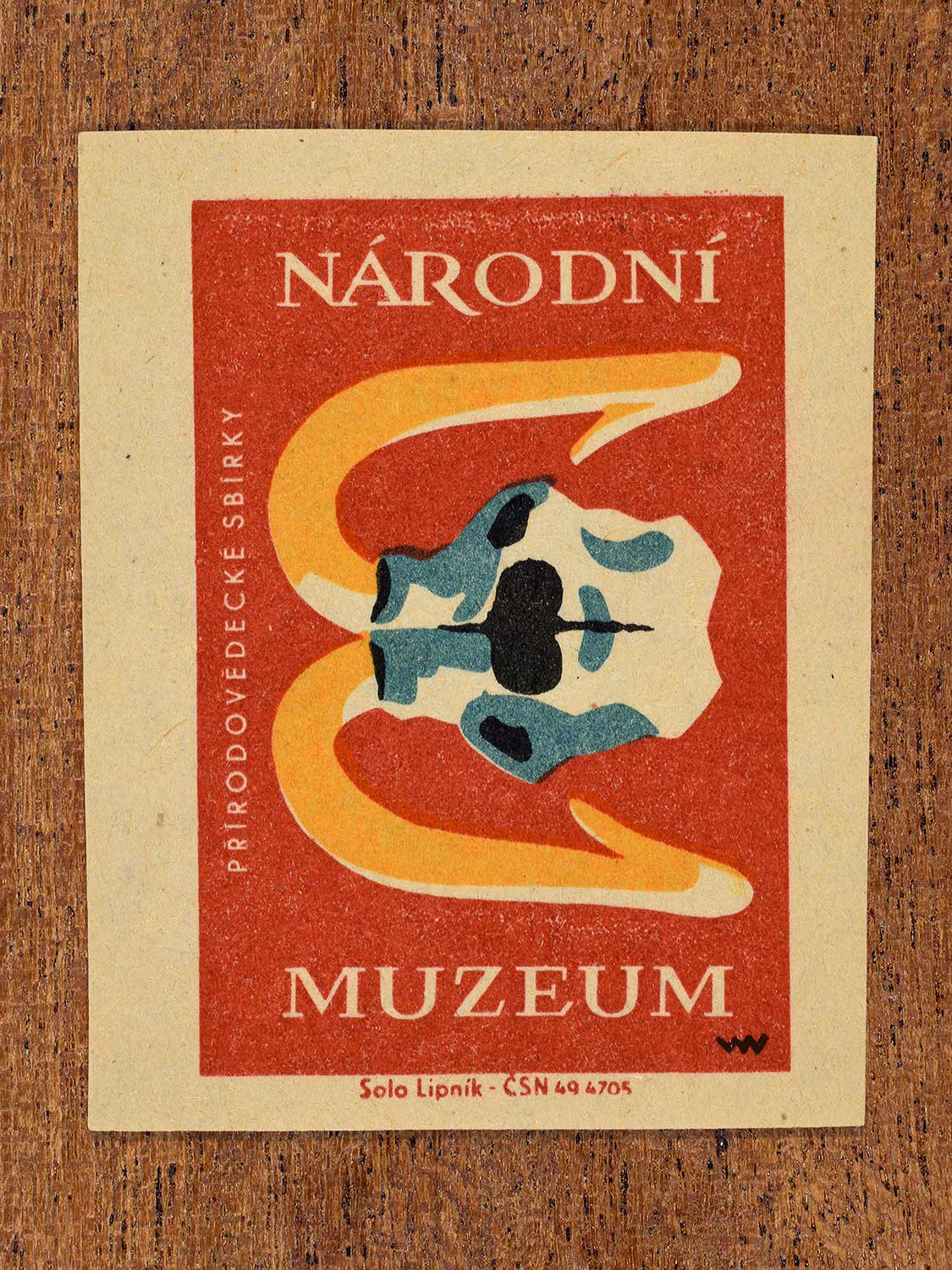 Vintage 1964 Czechoslovakia matchbox label showing a mammoth skull with long curved tusks in yellow, red and teal colours. Produced by the Solo Lipník match factory to promote the Národní Muzeum (National Museum) in Czechoslovakia.