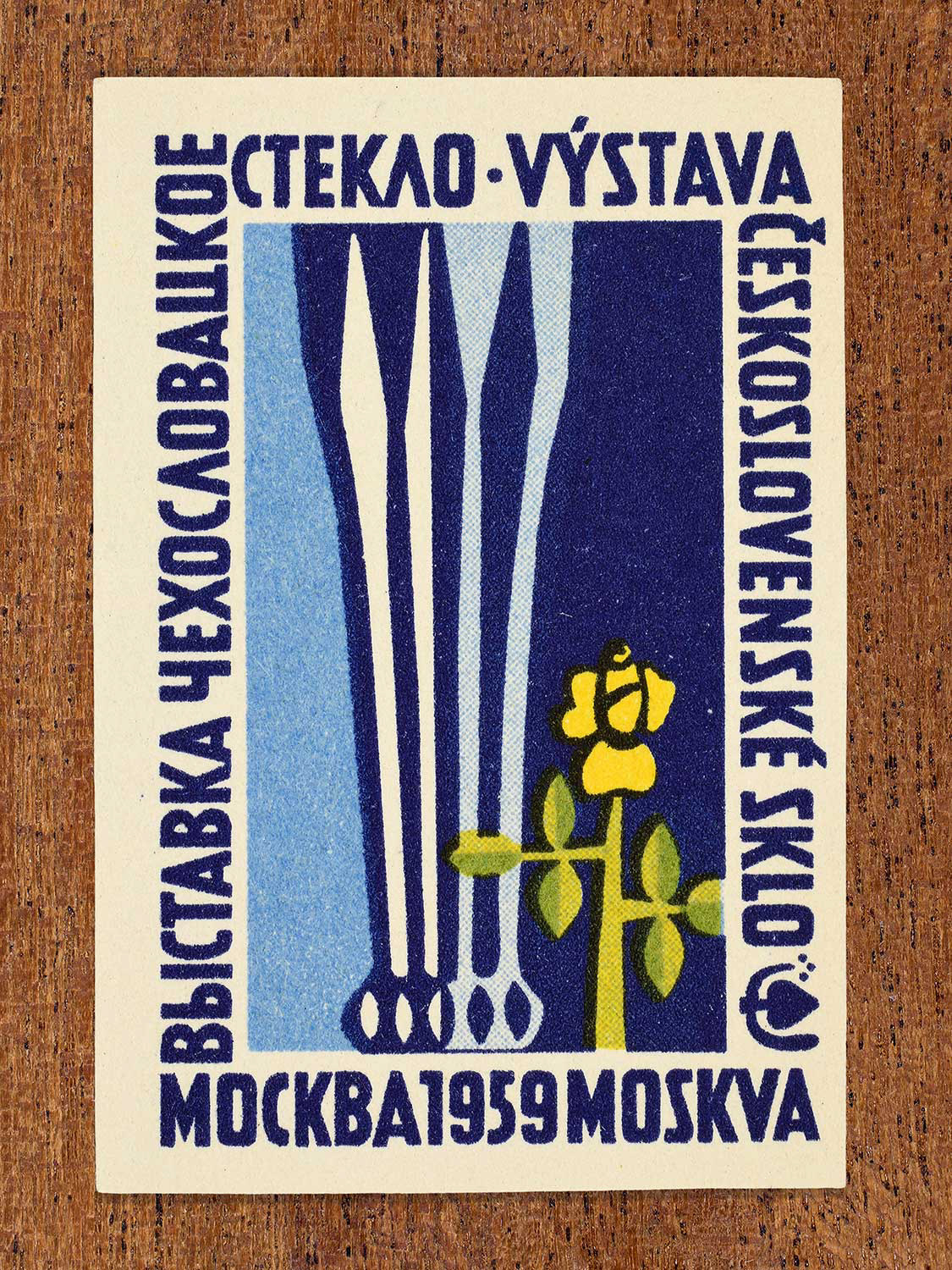 Mid-century modern Eastern Bloc artwork on a 1959 Czechoslovak matchbox label featuring a glass sculpture on a dark blue background. Designed to promote an international glass exhibition in Moscow by an unknown factory.
