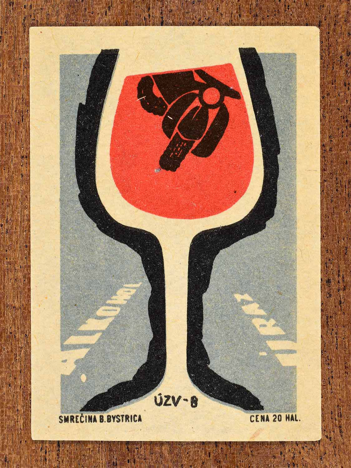 Vintage 1967 Czech matchbox label showing a large glass of red wine with a motorbike inside, on a grey background. Produced by the Smrečná match factory, Banská Bystrica, to caution against drink driving.