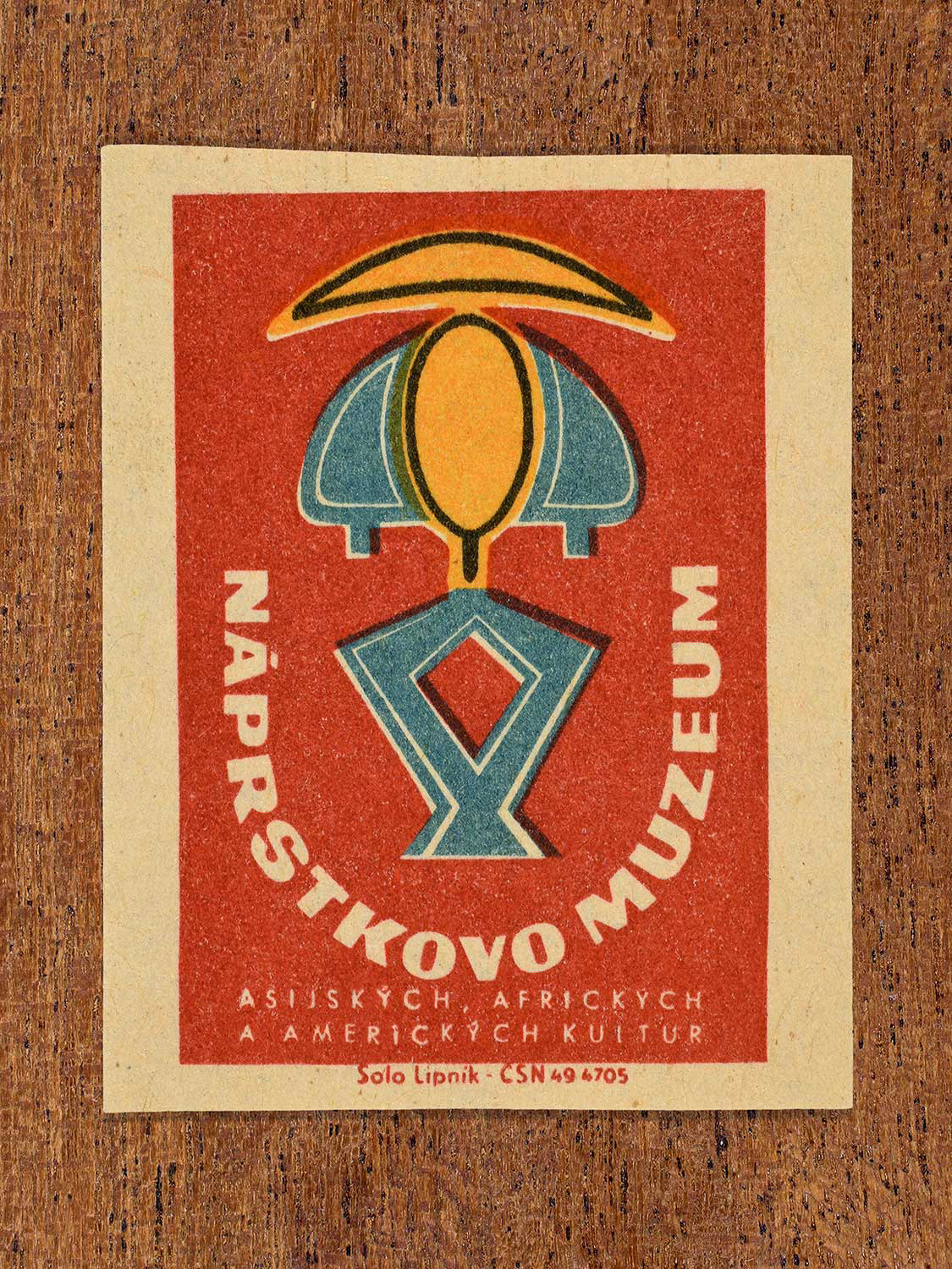 Vintage 1964 Czechoslovakia matchbox label showing an abstract emblem in black, yellow, teal and red colours. Produced by the Solo Lipník match factory to promote the Náprstkovo Muzeum (Náprstek Museum) in Czechoslovakia.