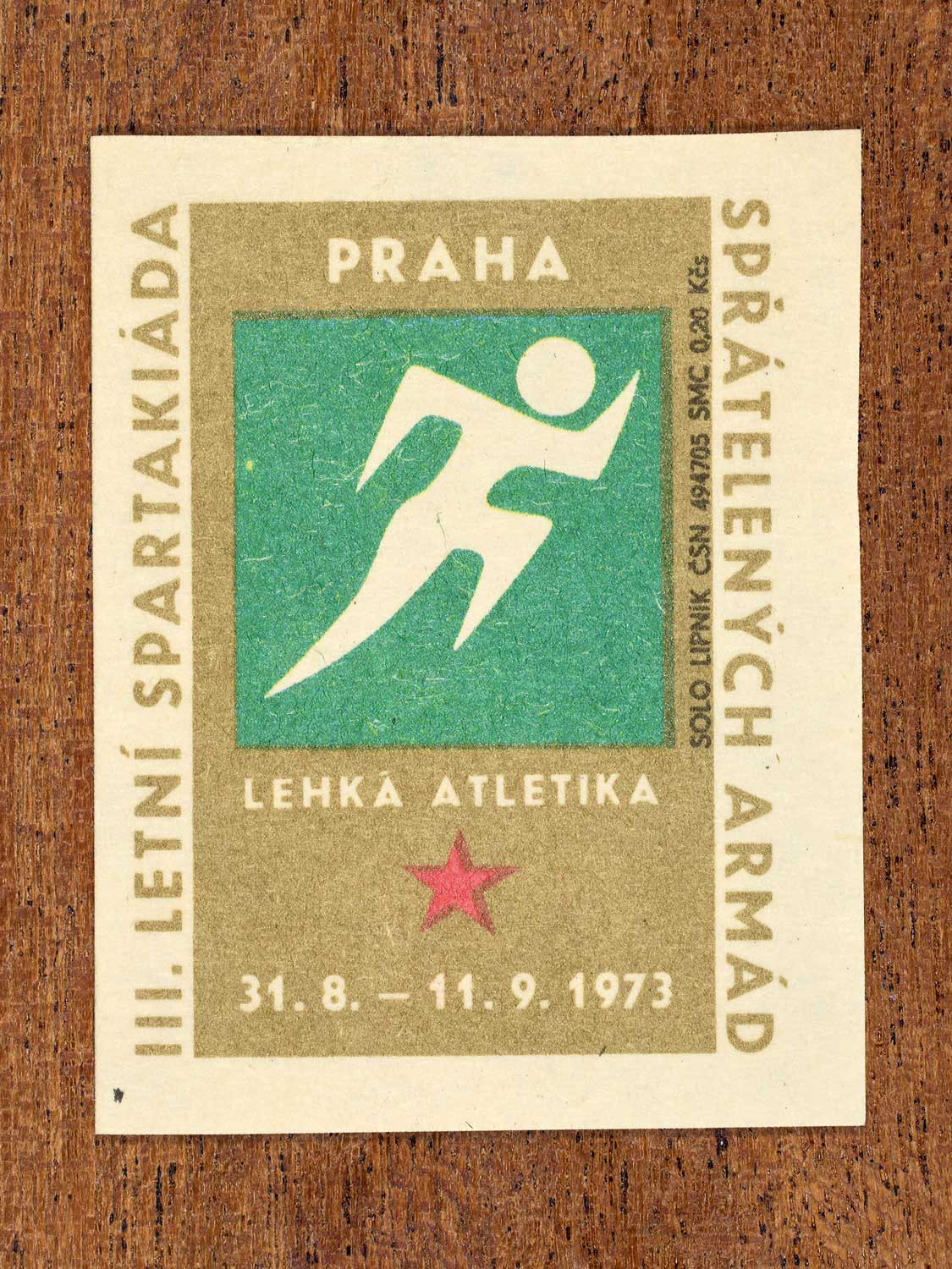 Vintage 1973 Czech matchbox label showing a simplified white figure sprinting on a green and gold background. Produced by the Solo Lipník match factory to promote physical training and demonstrate collective military readiness among allied armies.