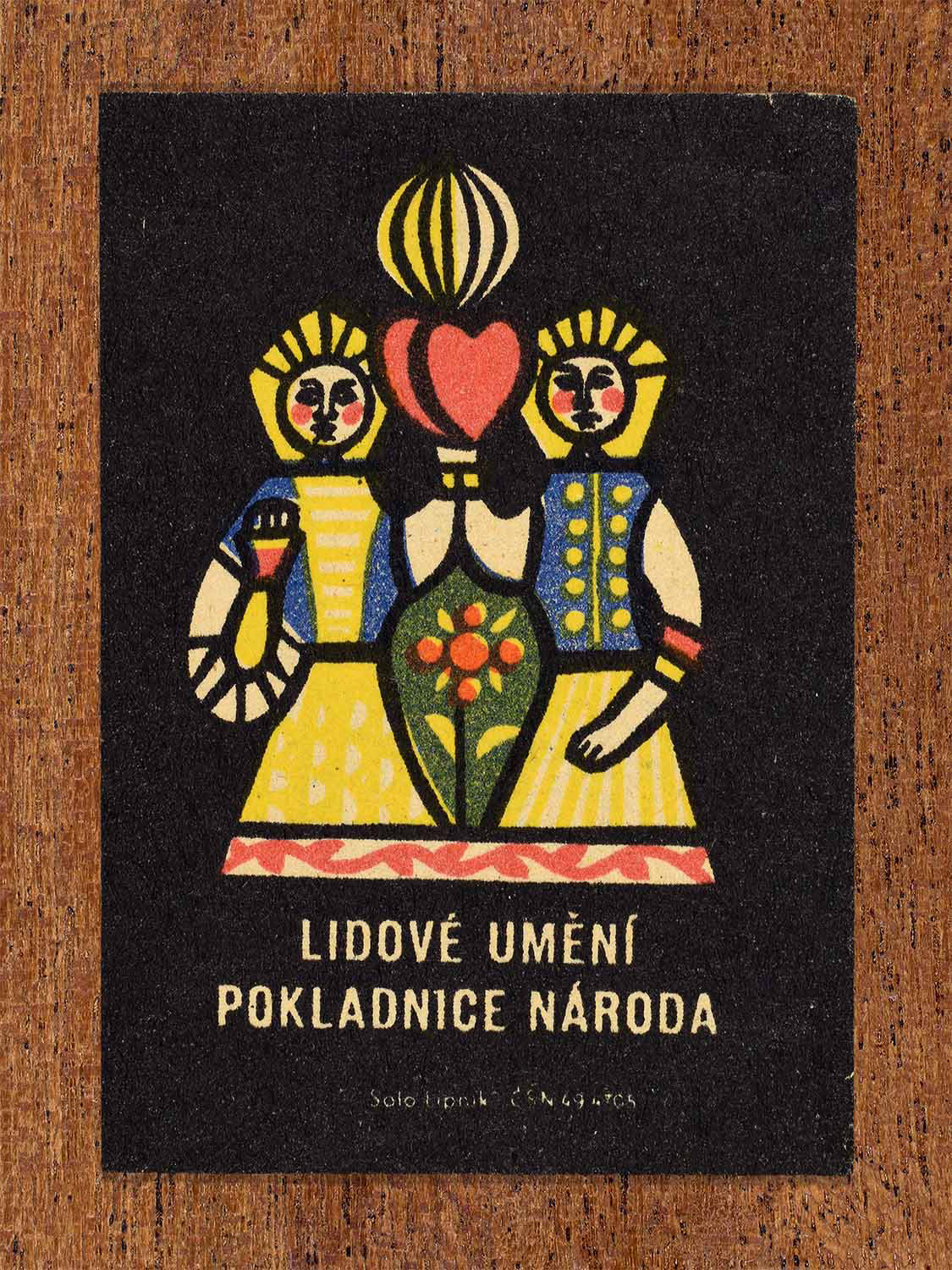 Vintage c. 1962 Czech matchbox label showing a traditional folk couple holding a heart in bright folkloric colours. Produced by the Solo Lipník match factory to promote appreciation of national folk traditions.