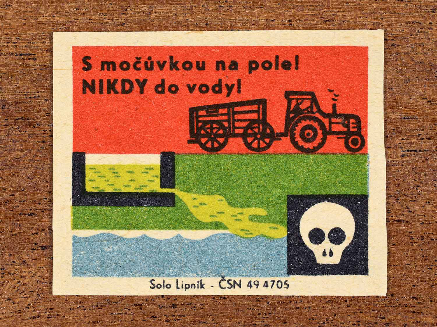 Vintage 1966 Czech matchbox label showing a farm tractor, livestock slurry tank and a skull warning symbol in red, green and blue colours. Produced by the Solo Lipník match factory to warn that agricultural slurry must not be discharged into water.