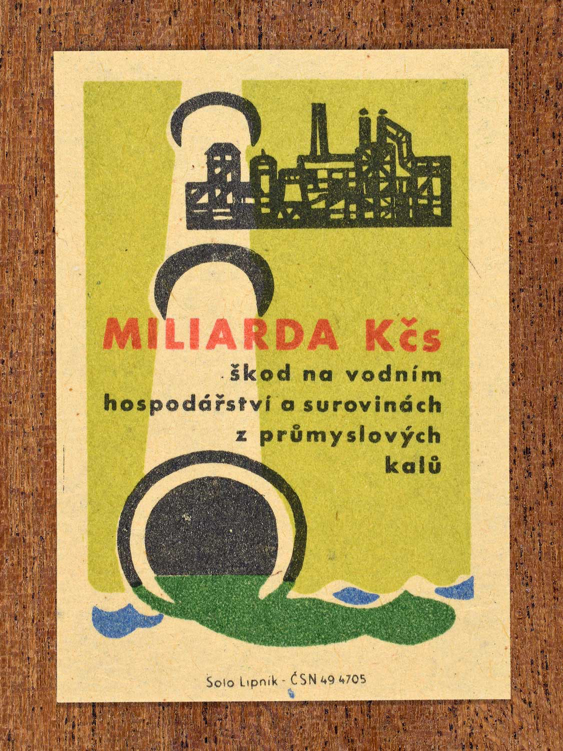 Vintage c. 1963 Czech matchbox label showing a factory draining green industrial sludge into water, in green, red and black colours. Produced by Solo Lipník match factory emphasising the billion-koruna economic damage pollution causes.