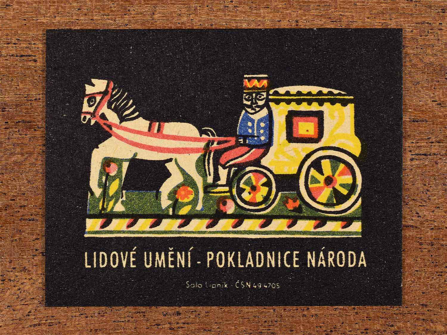 Vintage c. 1962 Czech matchbox label showing a stylised folk ornament depicting a horse-drawn carriage with a rider. Produced by the Solo Lipník match factory to honour national folk art traditions.