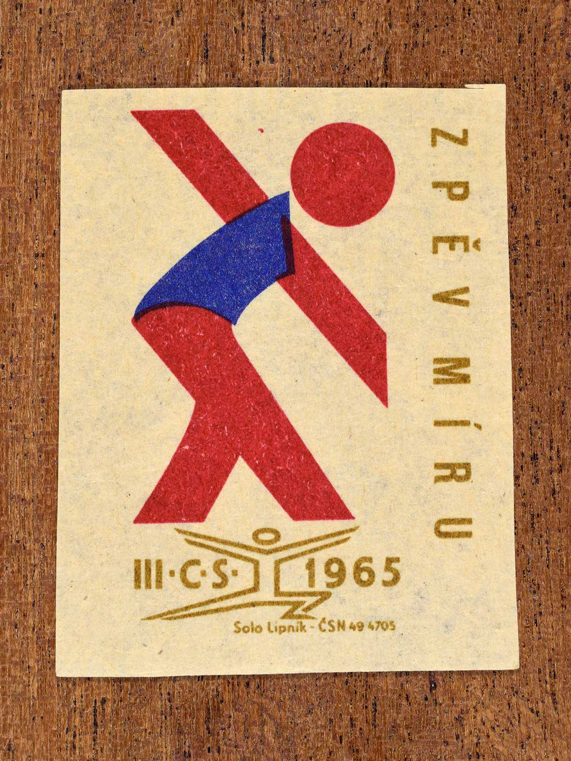 Vintage 1965 Czechoslovak matchbox label showing a stylised athlete figure in blue, red and gold colours. Produced by the Solo Lipník match factory to promote all-round physical fitness.