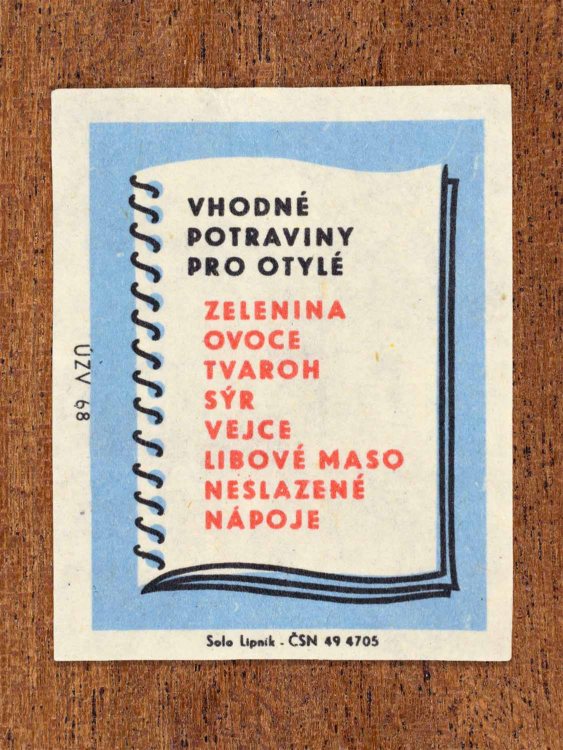 Vintage c. 1968 Czech matchbox label showing a notebook with handwritten-style list of suitable foods, on blue background. Produced by the Solo Lipník match factory to provide dietary guidance for overweight people.