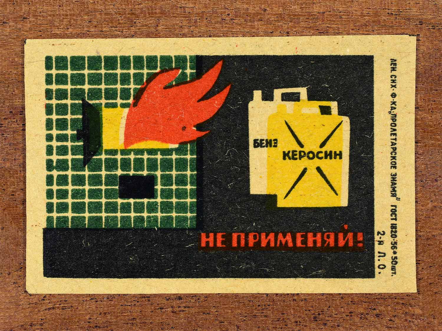 Vintage 1962 Soviet matchbox label showing petrol and kerosene containers near a burning building. In black, yellow, red and green colours. Produced by the Proletarian Banner match factory to warn against unsafe use of flammable liquids.