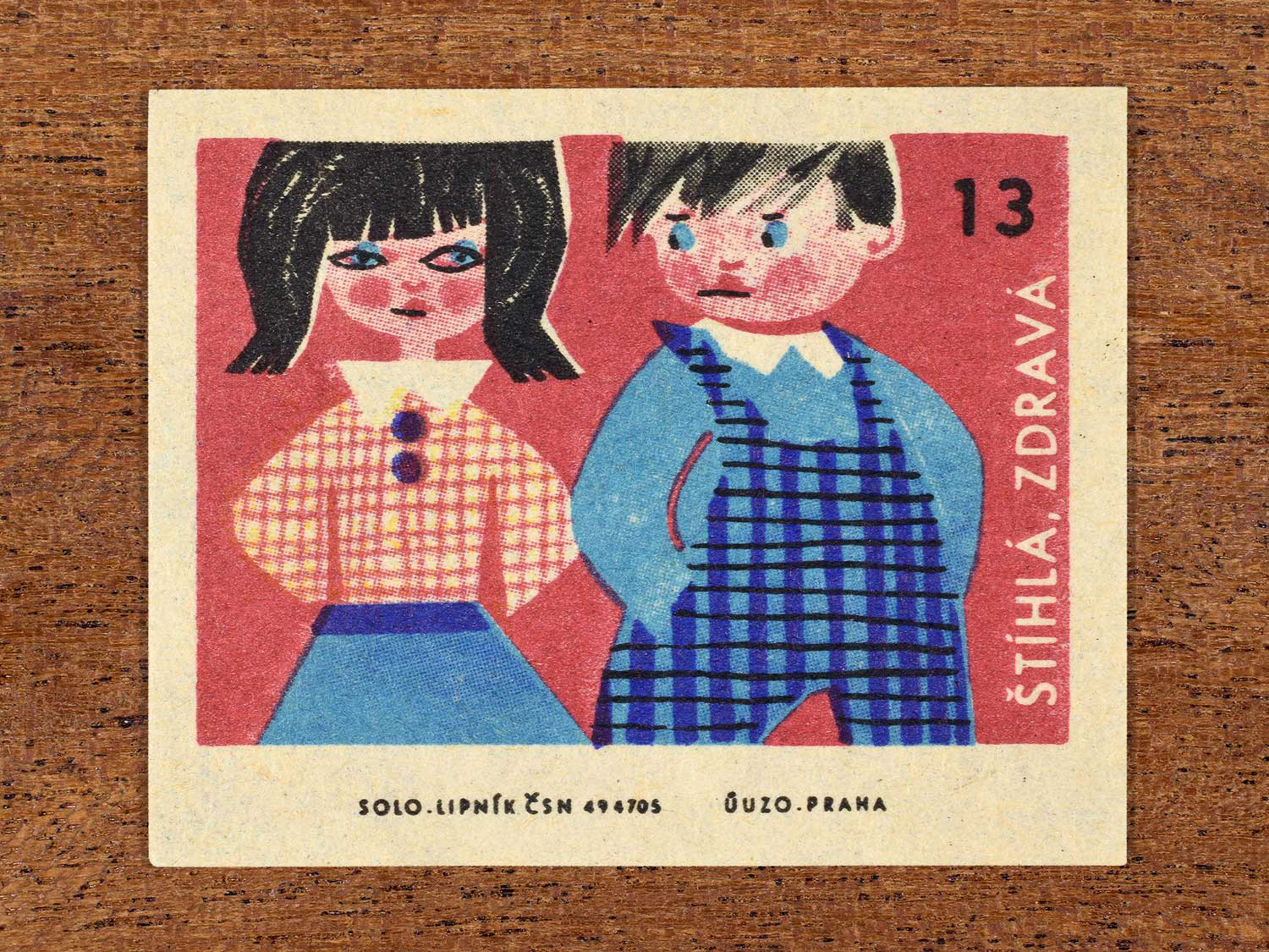 Vintage c. 1965 Czech matchbox label showing two children standing side by side and looking at each, on a red background. Produced by Solo Lipník match factory to promote the health benefits proper nutrition, daily meal routines, and everyday household habits.