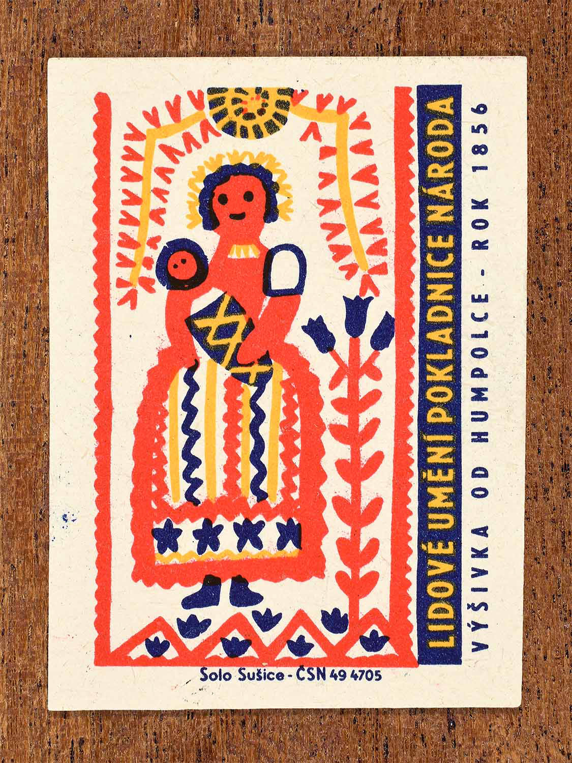 Vintage 1964 Czech matchbox label showing a stylised female folk figure with geometric and floral borders. Produced by the Solo Sušice match factory to illustrate traditional embroidery from the Doudleby region.