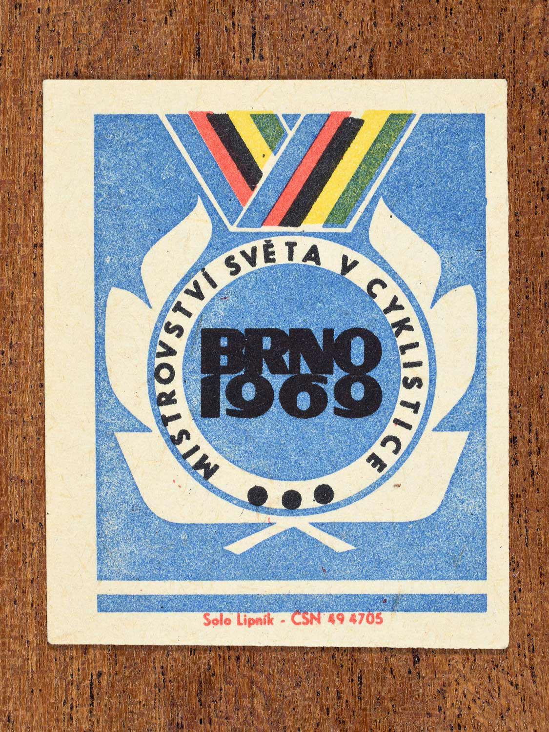 Vintage 1969 Czech matchbox label showing the emblem of a cycling championship with laurel wreath and BRNO 1969 lettering, on a blue background. Produced by the Solo Lipník match factory.