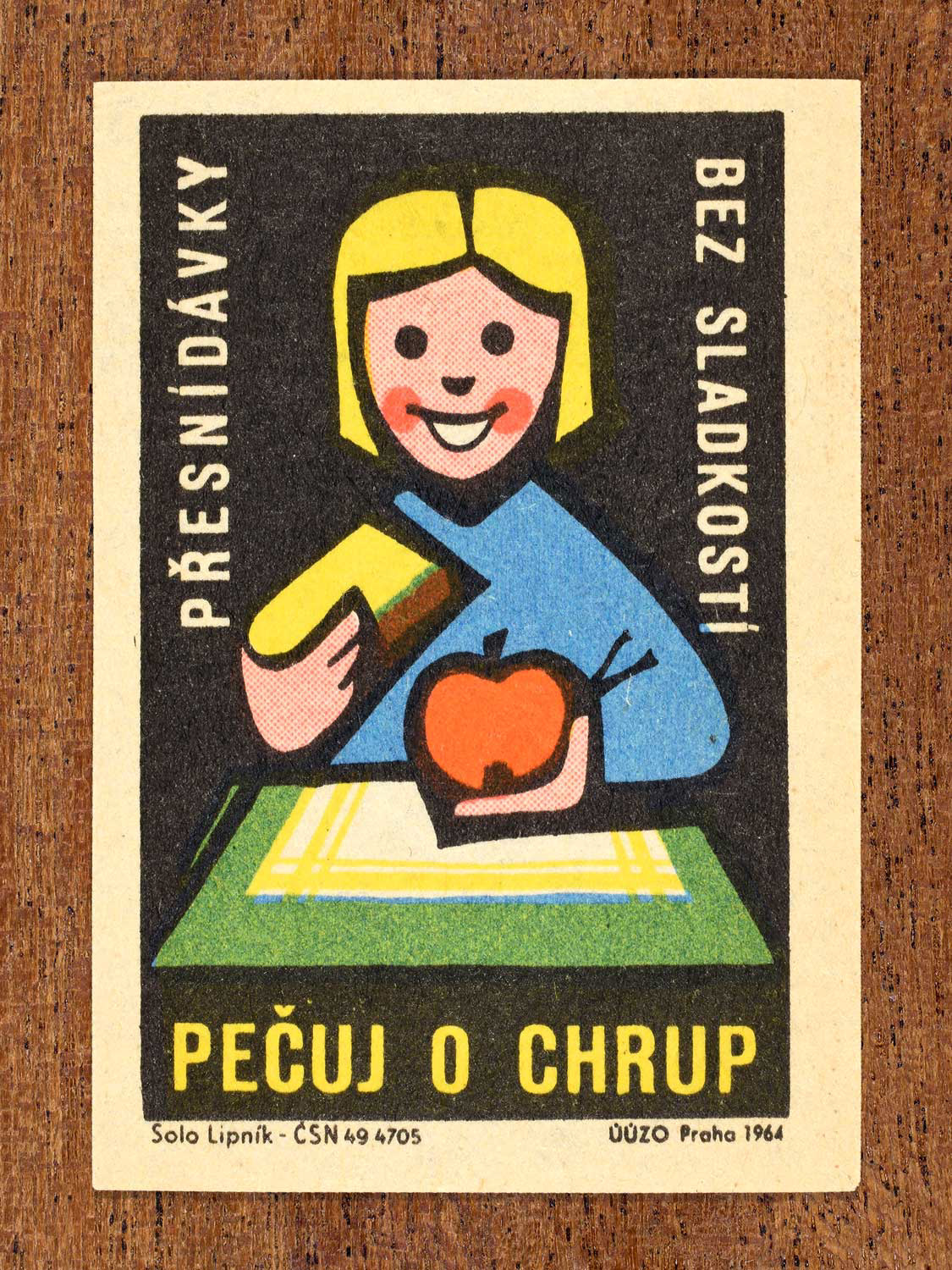 Vintage 1964 Czech matchbox label showing an illustrated child eating fruit at a table, on a black background. Produced by the Solo Lipník match factory to promote nutrition advice and hygiene habits in protecting healthy teeth.