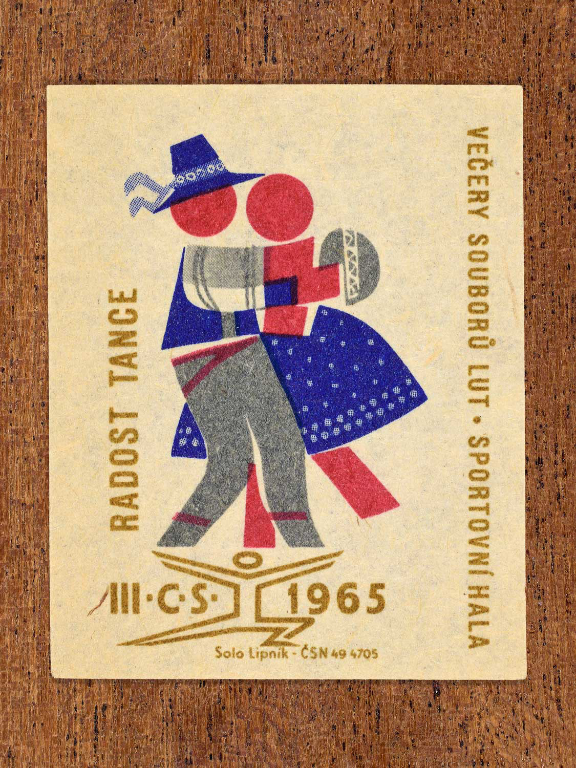 Vintage 1965 Czechoslovak matchbox label showing two stylised folk dancers in blue, red and gold colours. Produced by the Solo Lipník match factory to promote joyful social dance.
