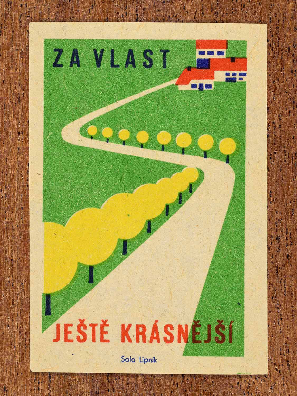Vintage 1960 Czech matchbox label showing a winding white road lined with trees leading towards buildings in a green landscape. Produced by the Solo Lipník match factory to encourage orderly urban planning and landscape improvement.