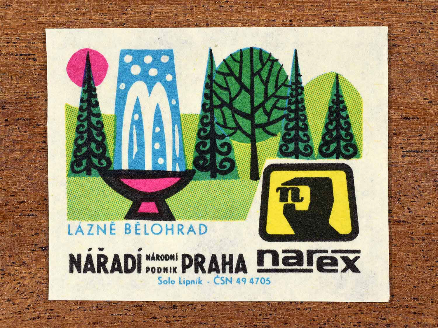 Vintage 1967 Czech matchbox label showing a fountain and landscaped park with trees in bright green, blue and pink. Produced by the Solo Lipník match factory to promote Bělohrad Spa and Narex, the national tool enterprise in Czechoslovakia.