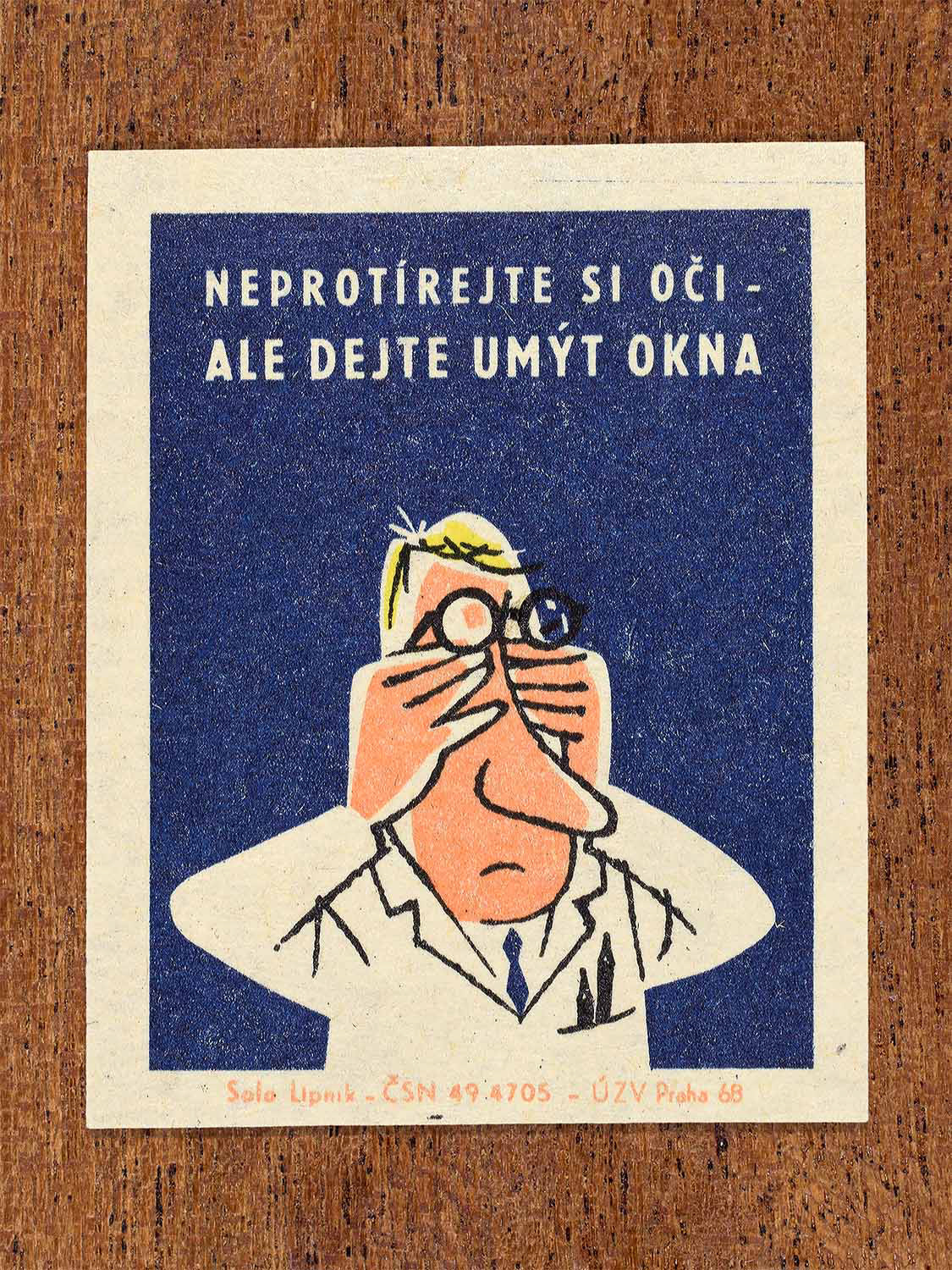 Vintage 1968 Czech matchbox label featuring a cartoon person wearing a lab coat and glasses rubbing their eyes, on blue background. Produced by Solo Lipník match factory to promote proper lighting and maintenance for eye health and safe work practices.