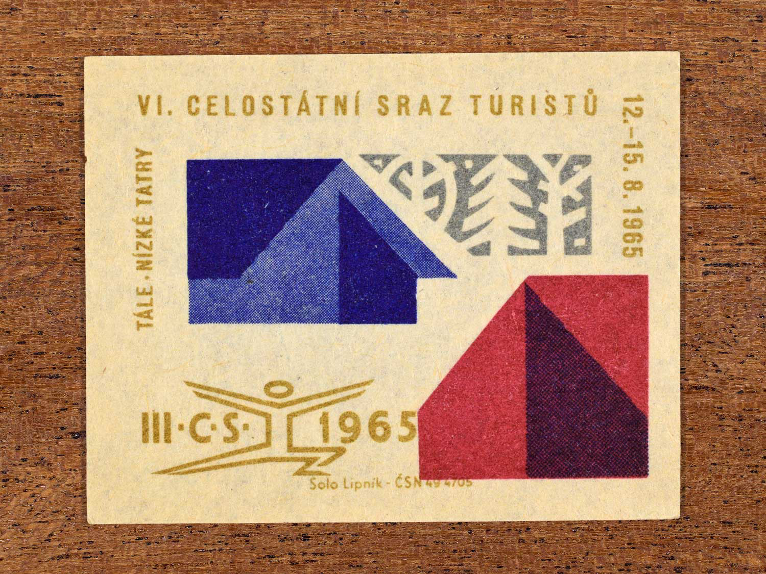 Vintage 1965 Czechoslovak matchbox label showing an abstract woodland scene with two cabins, in blue, red and gold colours. Produced by the Solo Lipník match factory to promote physical fitness and sporting achievement.