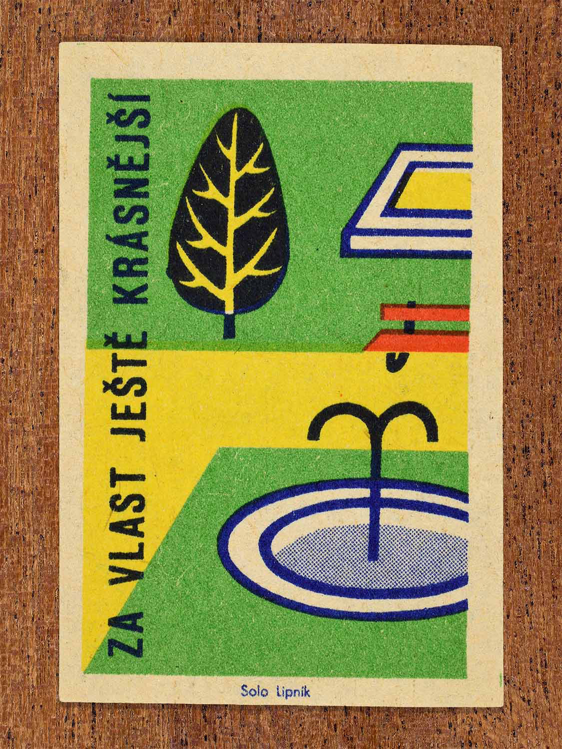 Vintage 1960 Czech matchbox label showing a public park scene with a fountain, bench and tree in green, yellow, red and blue colours. Produced by the Solo Lipník match factory to promote attractive public spaces and civic beautification.