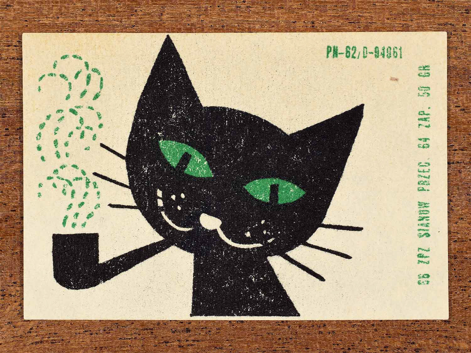 Vintage 1966 Polish matchbox label showing a stylised black cat smoking a pipe with white dotted smoke on a white background. Produced by the Sianów match factory in Poland as retail packaging for safety matches.