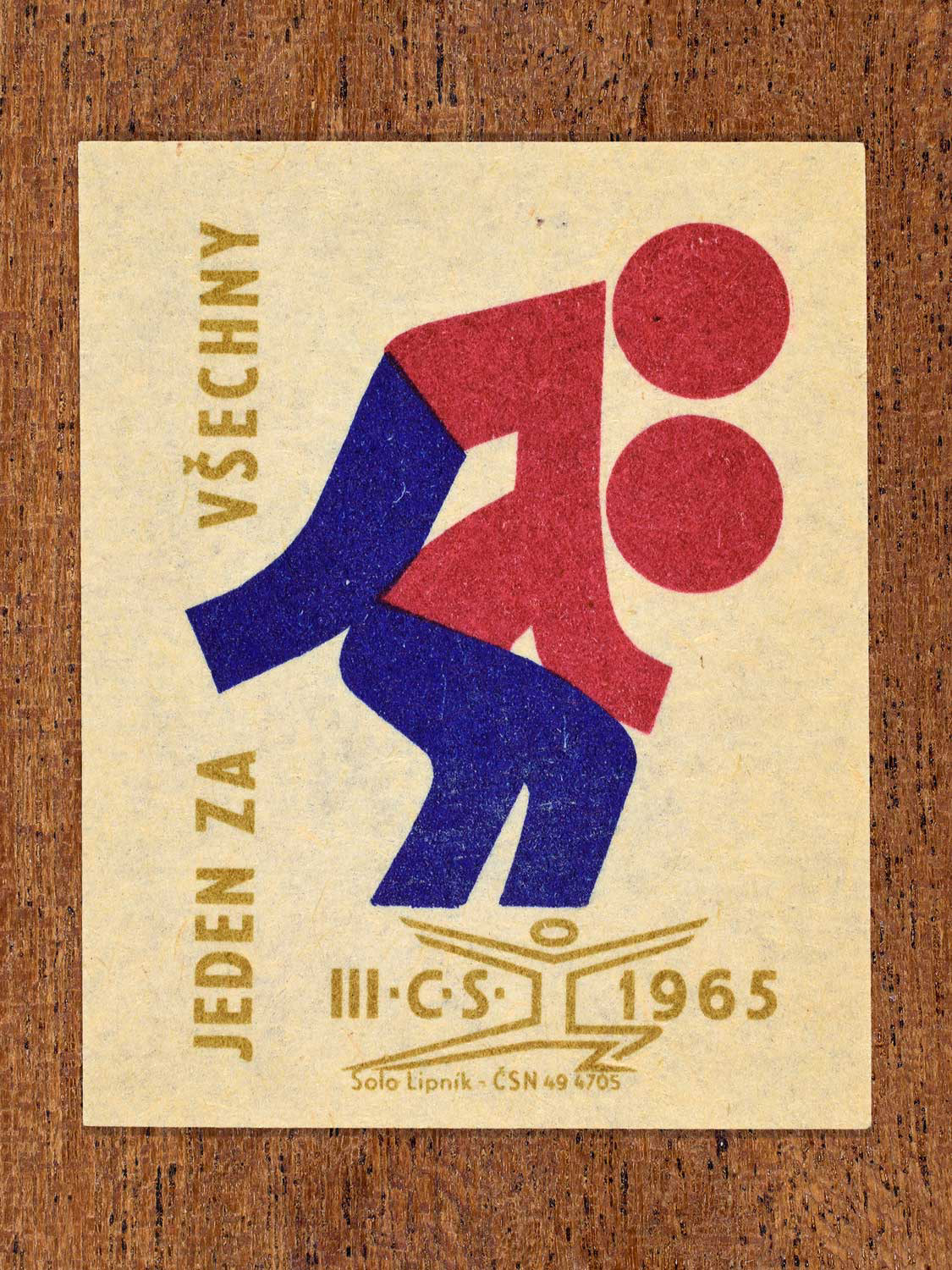 Vintage 1965 Czechoslovak matchbox label showing two abstract athlete figures, in blue, red and gold colours. Produced by the Solo Lipník match factory to promote physical fitness and sporting achievement.