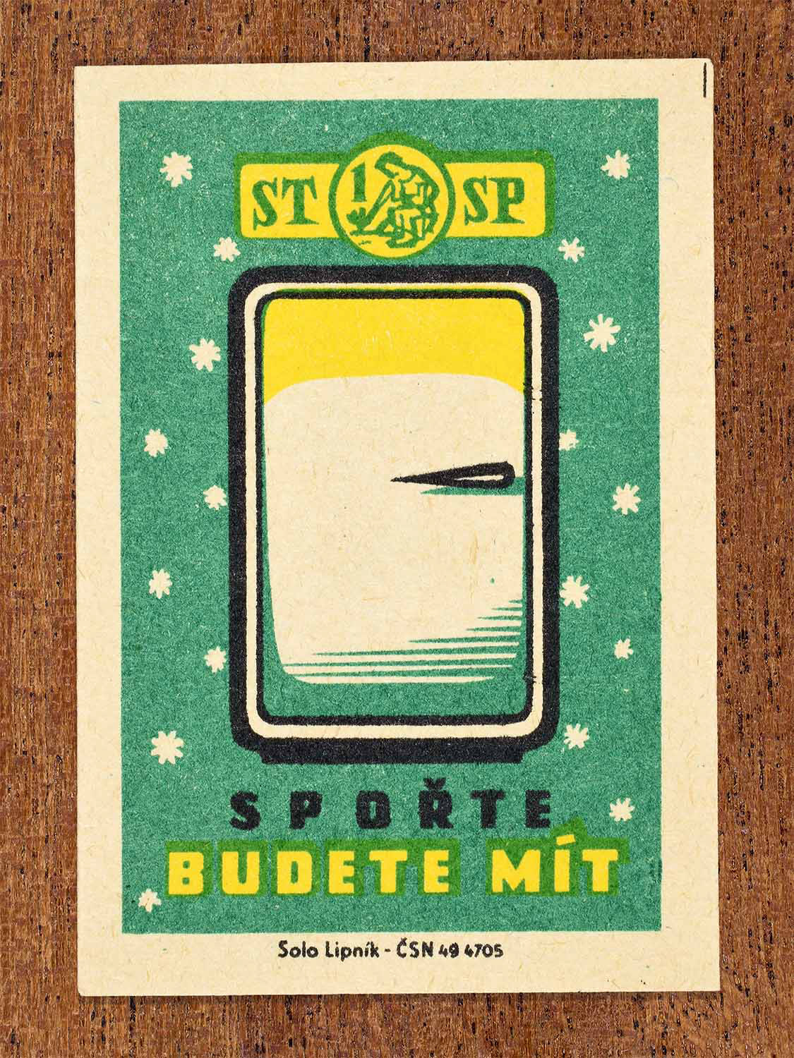 Vintage 1960 Czech matchbox label showing a refrigerator on a green background. Produced by the Solo Lipník match factory to promote saving as a means to obtain household appliances.