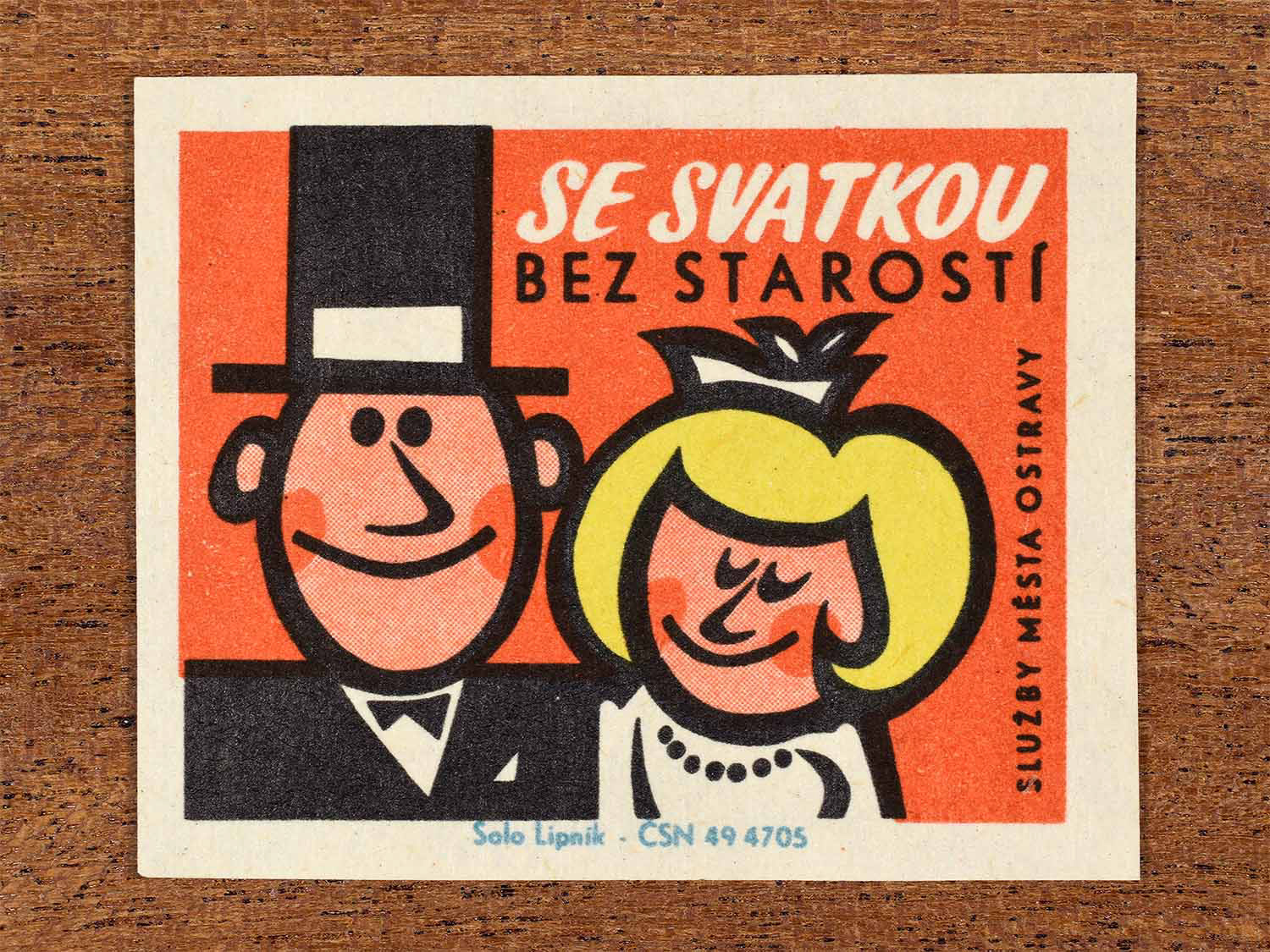 Vintage 1967 Czech matchbox label showing a married cartoon couple, on a red background. Produced by the Solo Lipník match factory to promote municipal services assisting during holidays.
