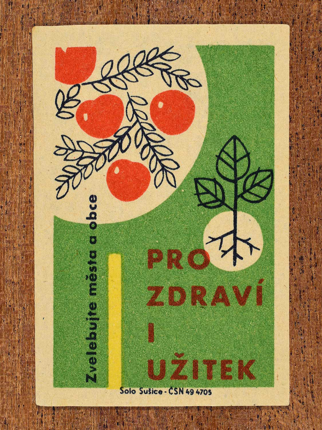 Vintage 1961 Czech matchbox label showing red apples hanging from branches and a young plant sprout with exposed roots, on a green background. Produced by the Solo Sušice match factory to promote growing home orchards and crops for health and utility.