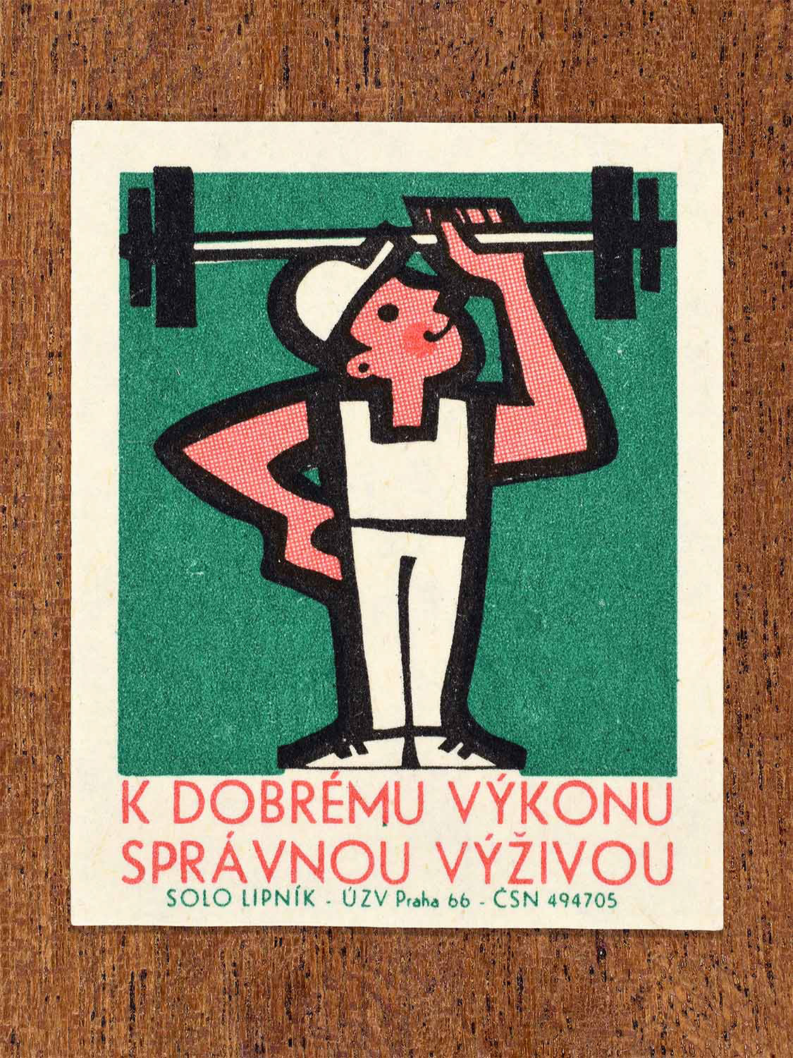 Vintage 1966 Czech matchbox label showing a weightlifter in white holding a barbell overhead. Produced by the Solo Lipník match factory to promote proper nutrition for physical strength and performance.
