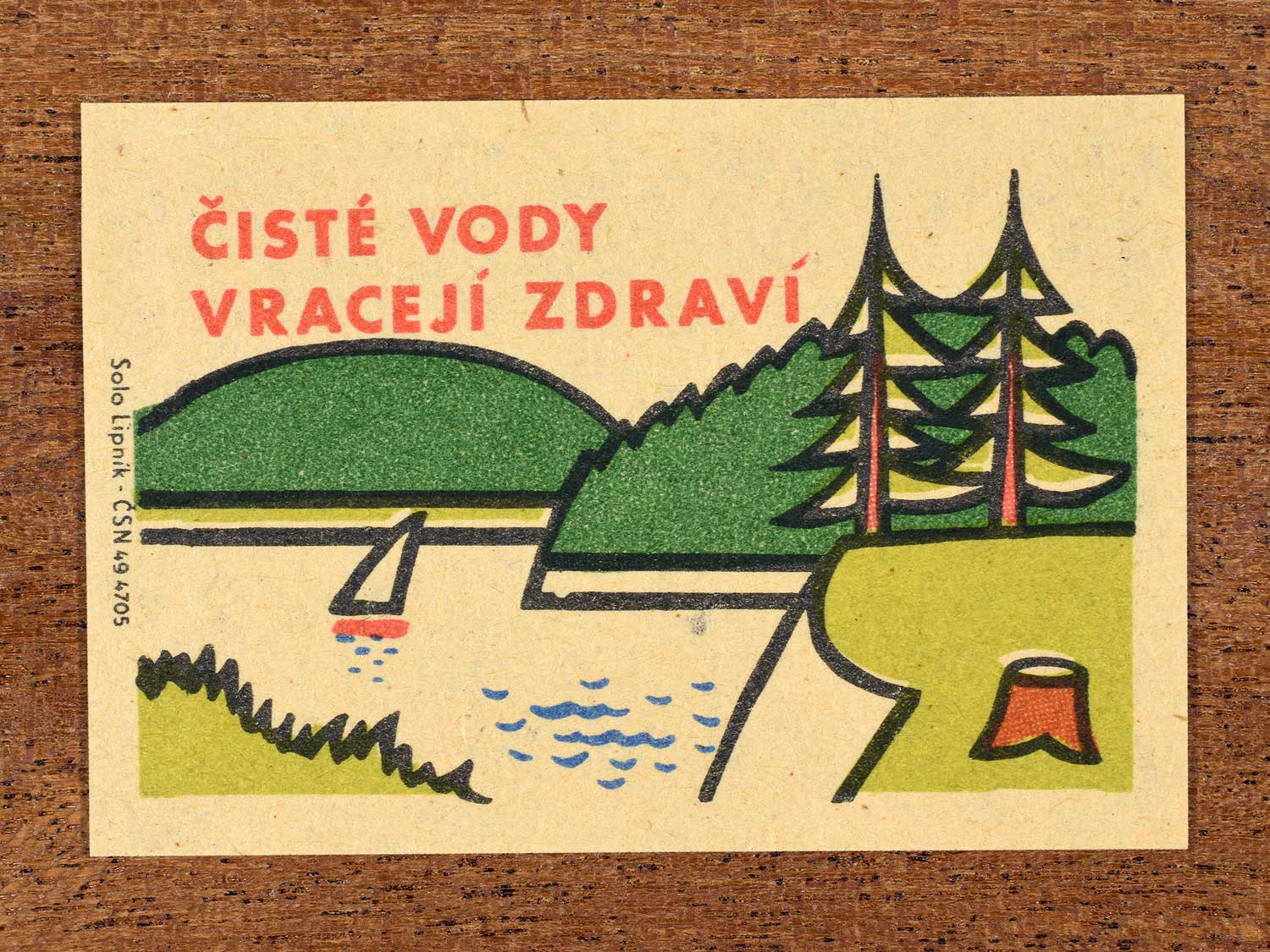 Vintage c. 1963 Czech matchbox label showing a clean lake with trees and a small house, in green, red and black colours. Produced by Solo Lipník match factory promoting the health benefits of clean water.