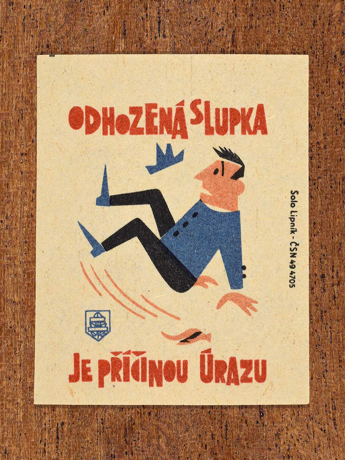 Vintage 1964 Czech matchbox label showing a person slipping on a discarded peel, in blue, red and black colours. Produced by the Solo Lipník match factory to warn against careless littering that can cause accidents.