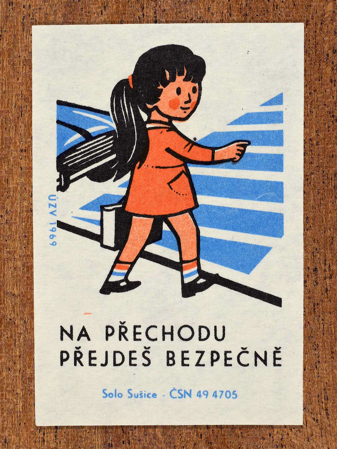 Vintage 1969 Czech matchbox label showing a young girl with a ponytail walking confidently across a blue and white striped zebra pedestrian crossing. Produced by the Solo Sušice match factory to promote safe street crossing using designated crosswalks.