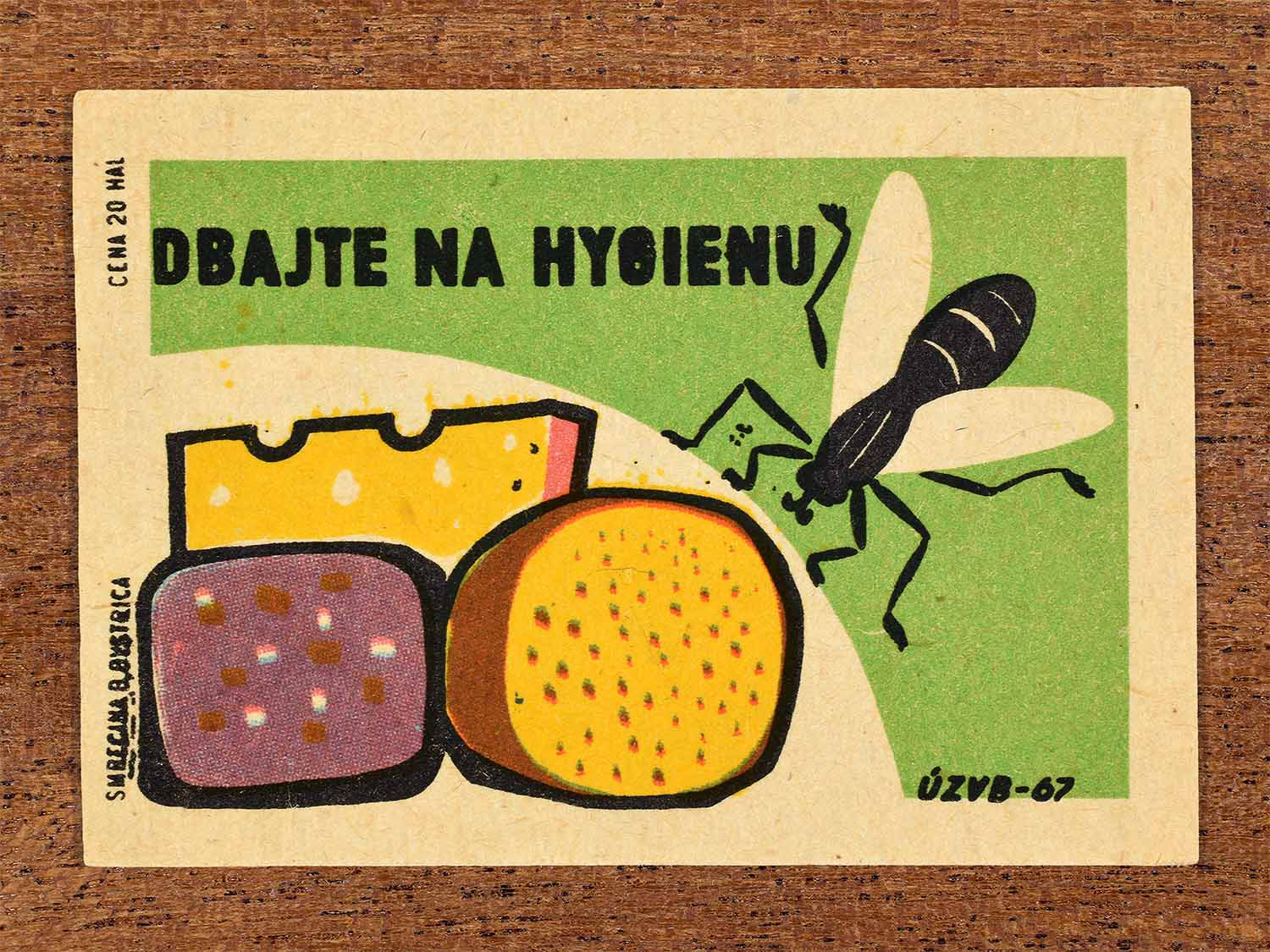 Vintage 1967 Czech matchbox label showing three covered cheeses and a fly, on a green background. Produced by the Smrečná match factory, Banská Bystrica, to stress the importance of food hygiene.